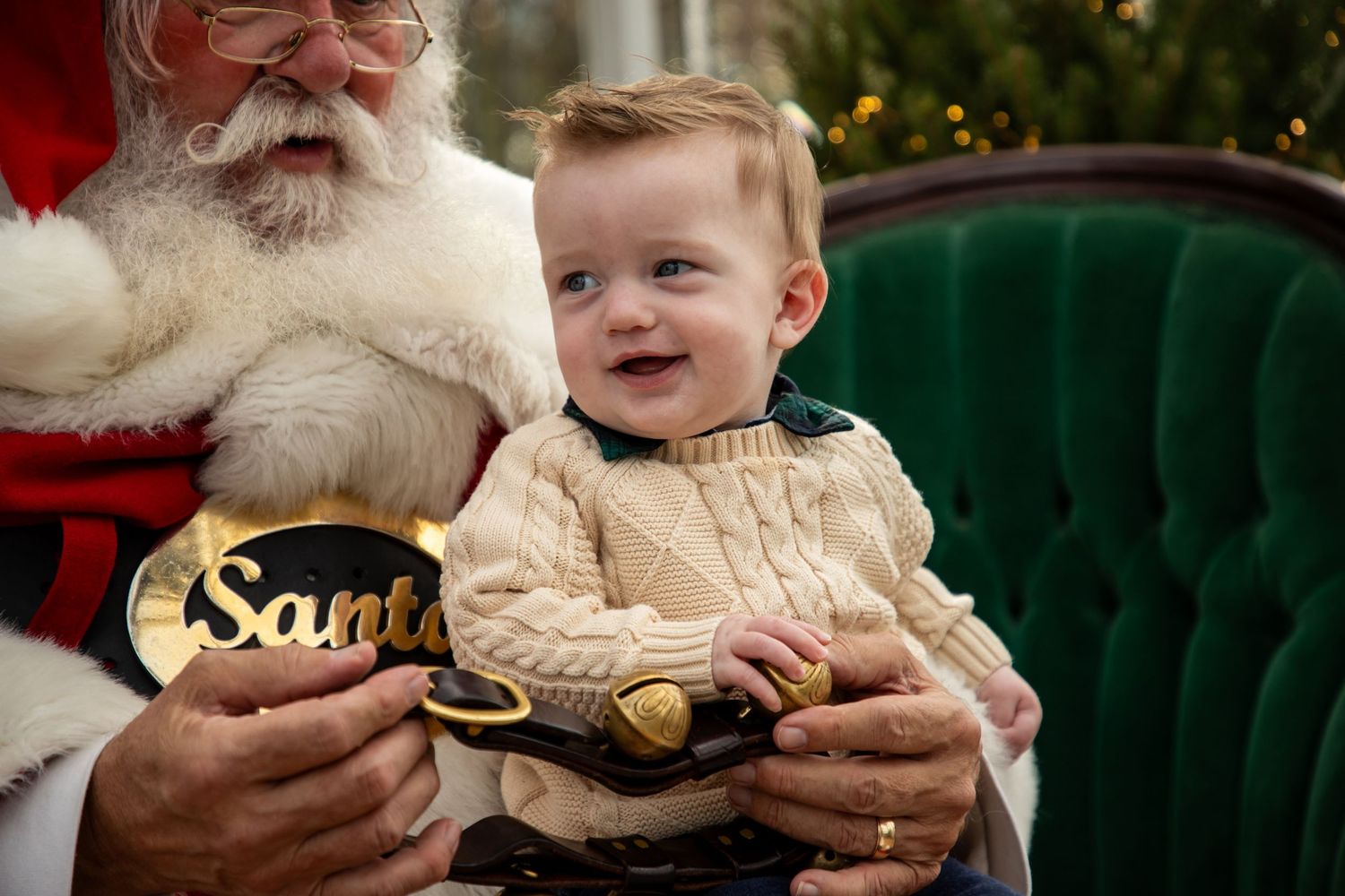 Holiday portraits with Santa Claus seated on a luxurious green velvet chair.