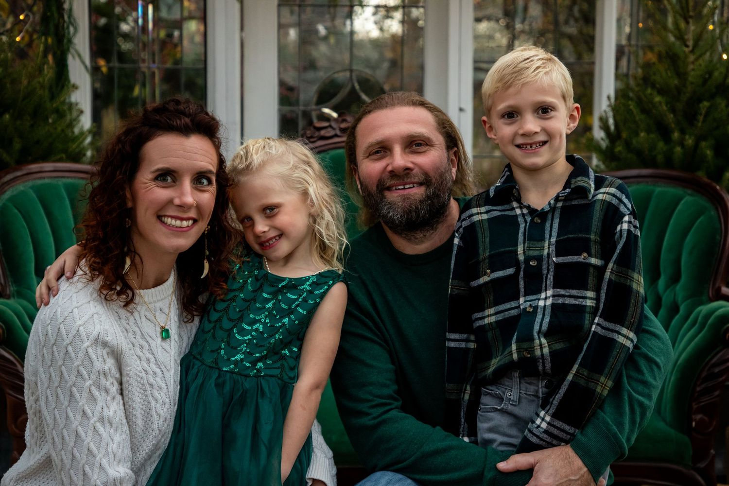 Family group portrait outdoors with green foliage background.