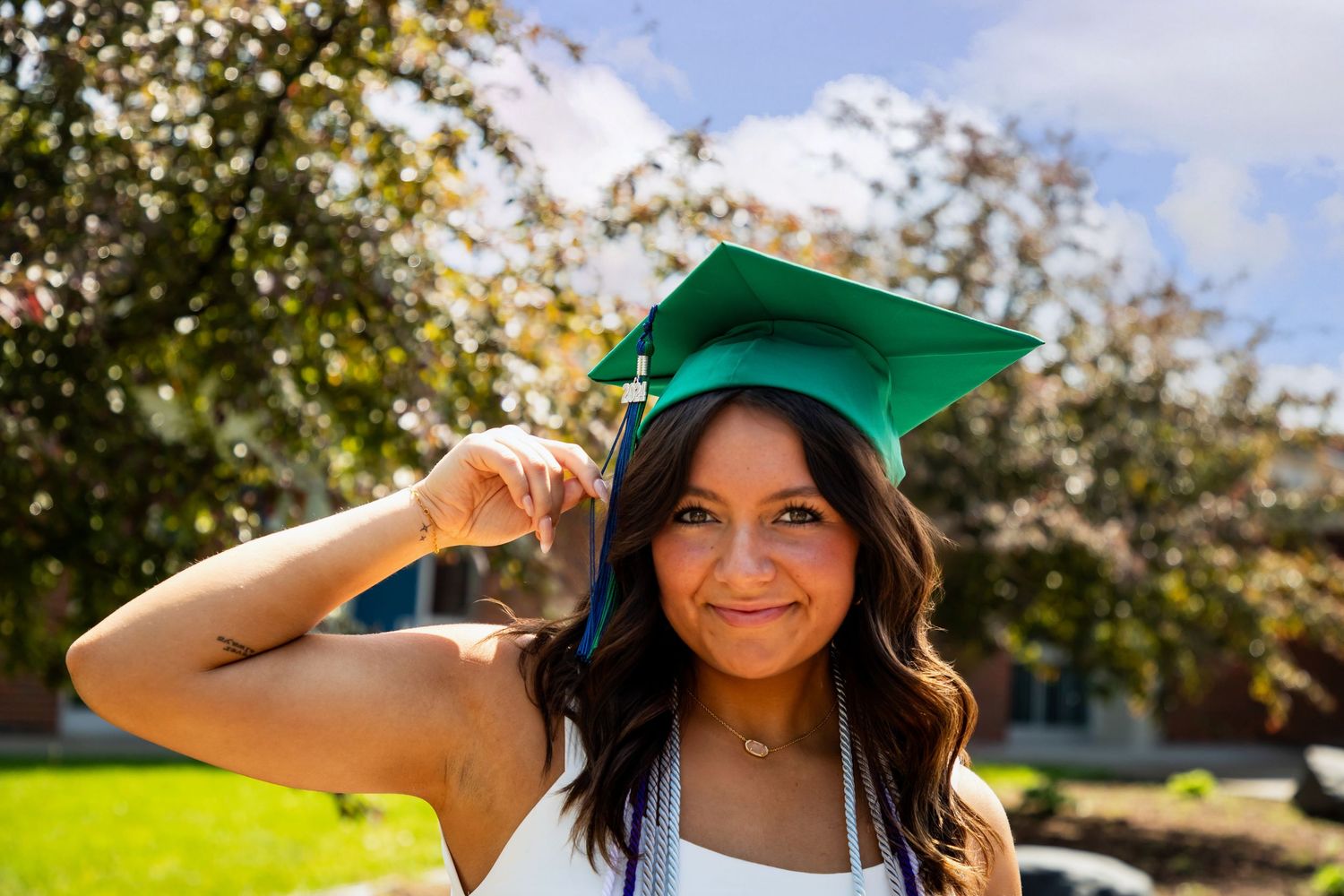 Outdoor graduation photos with someone wearing a green cap in bright sunlight.