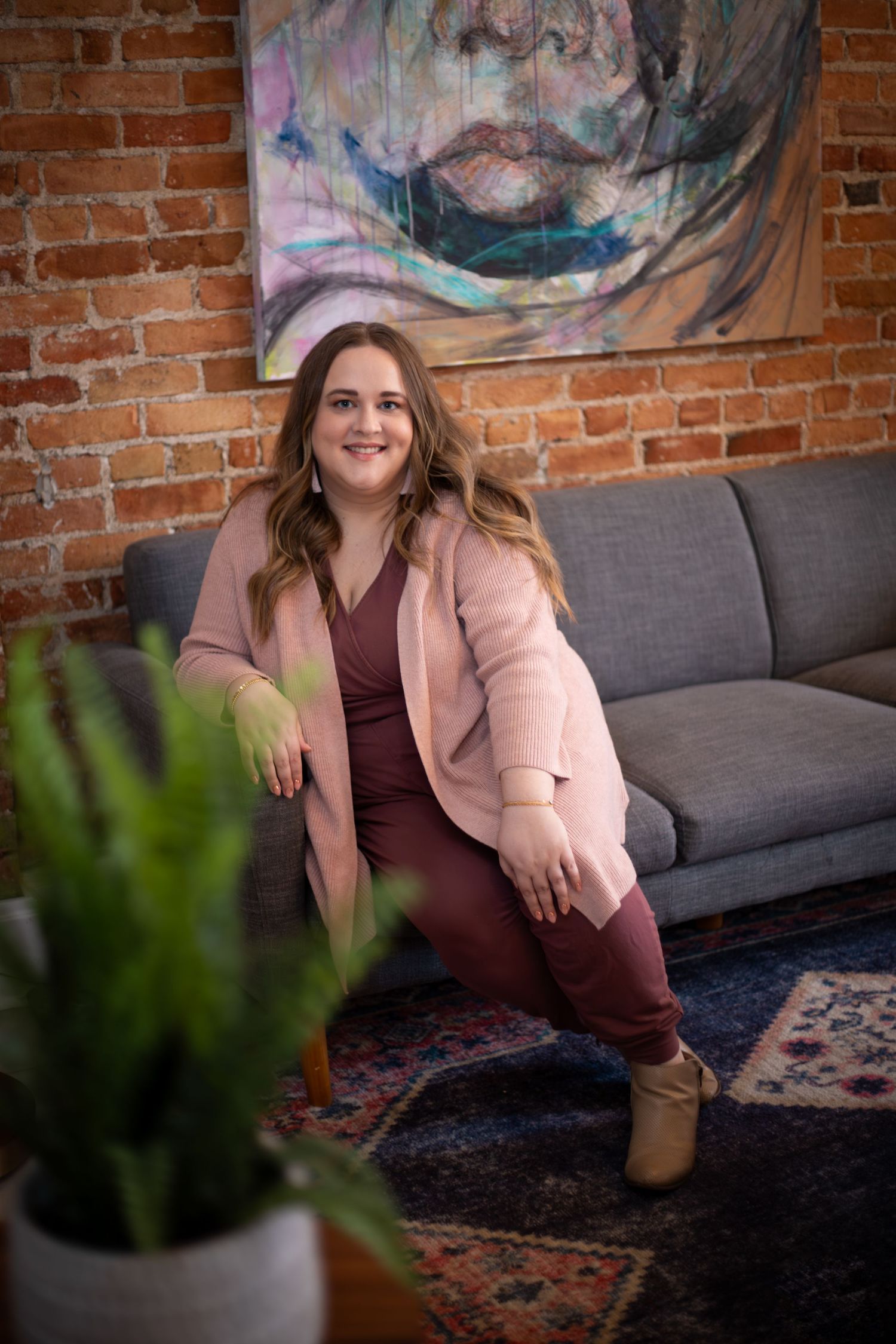 Lifestyle portrait session in modern space with exposed brick wall and colorful artwork.
