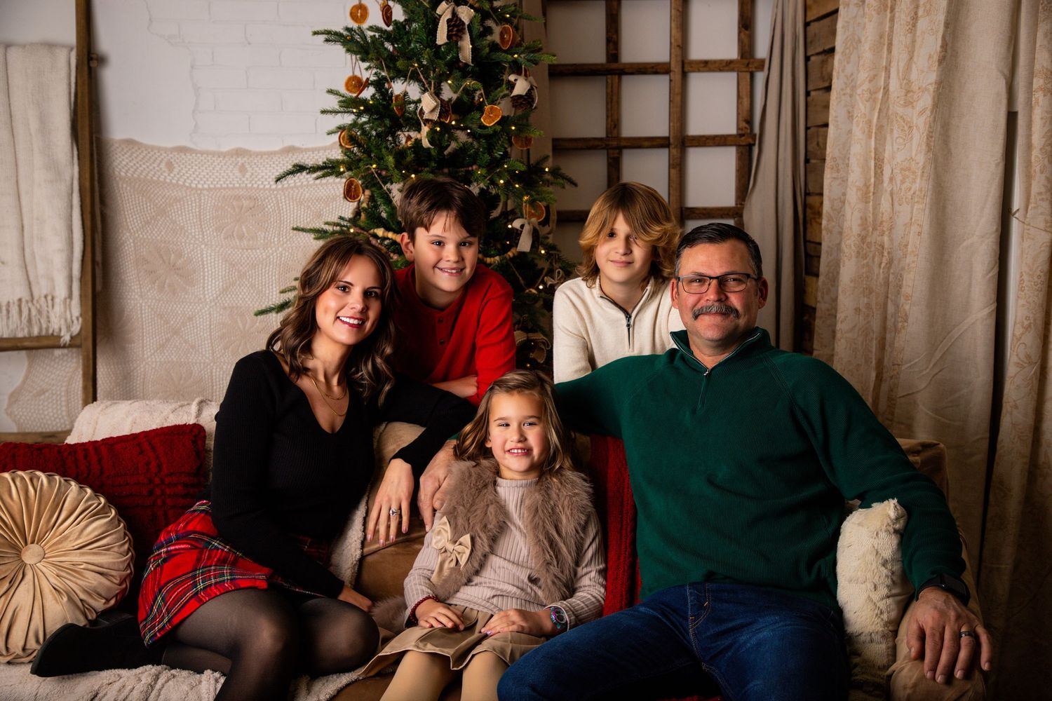 Family holiday portrait by Christmas tree in cozy living room with lattice wall decor.