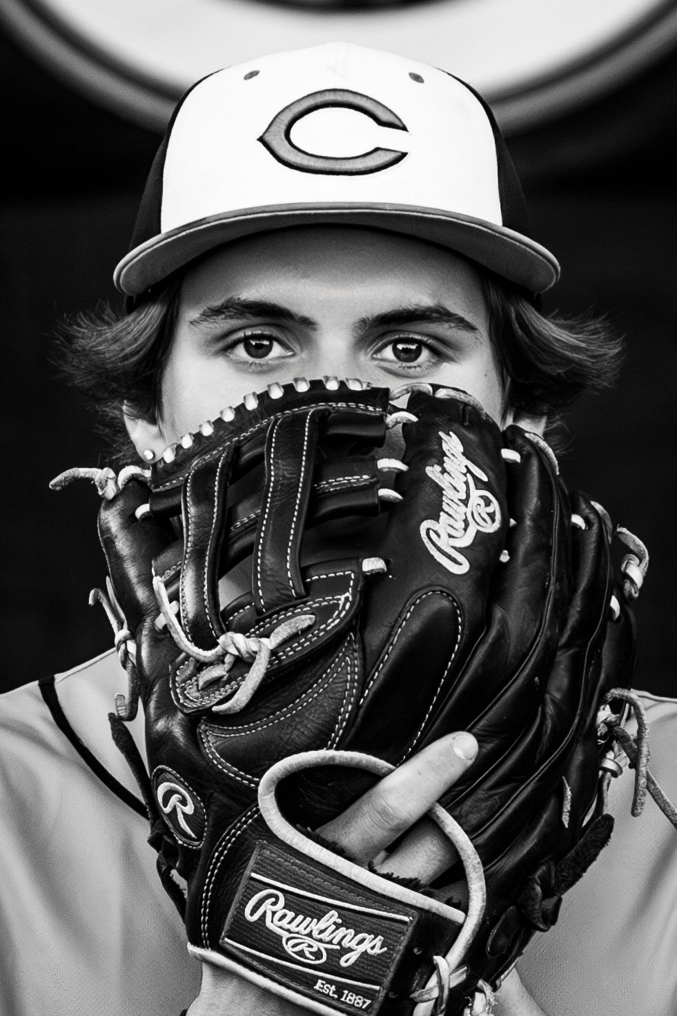 Black and white close-up of baseball glove and cap showing team logo.