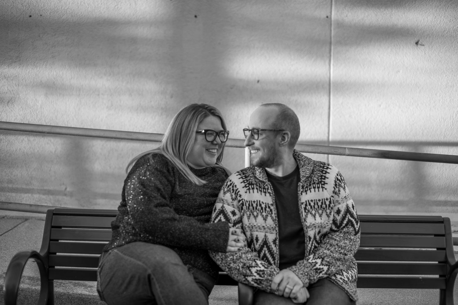 Winter maternity photos on a bench showing intimate couple moments in black and white.