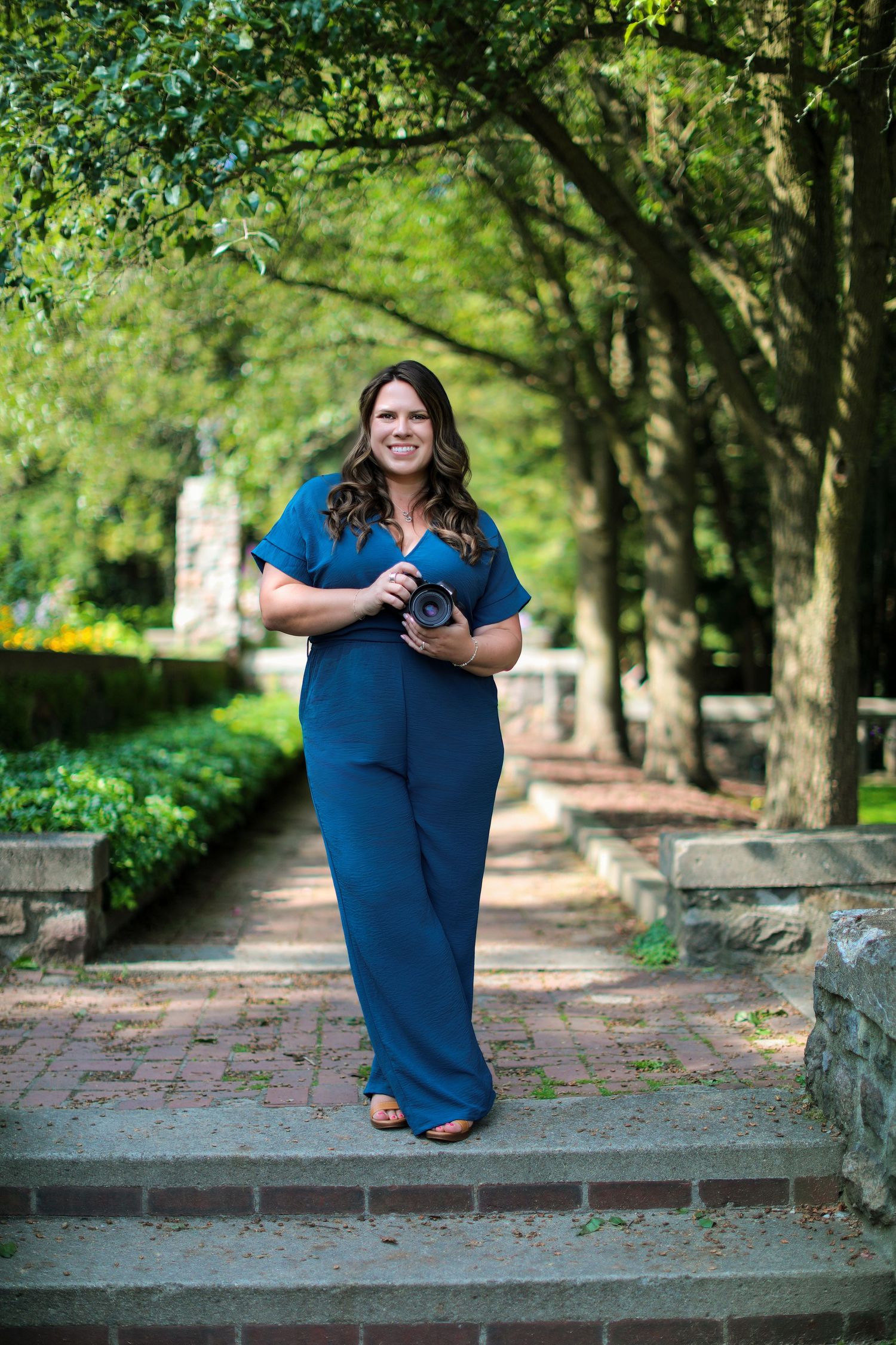 Professional photography session in blue dress on brick pathway with garden backdrop.