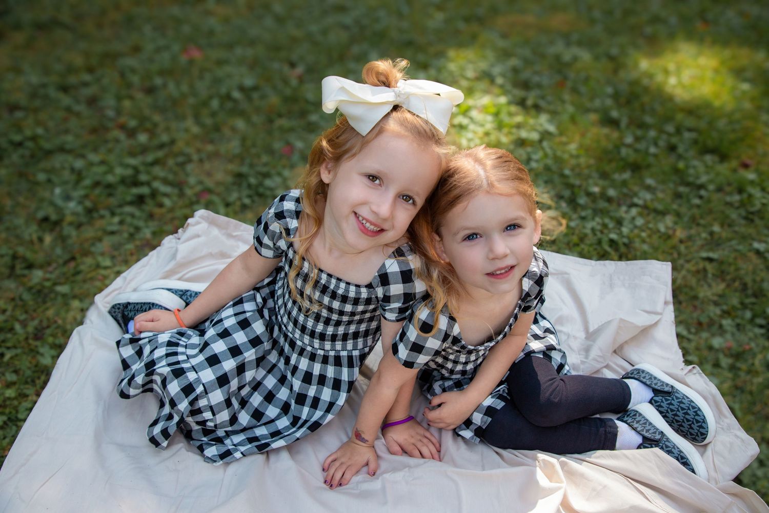 Family group relaxing together on blanket during outdoor photo session.