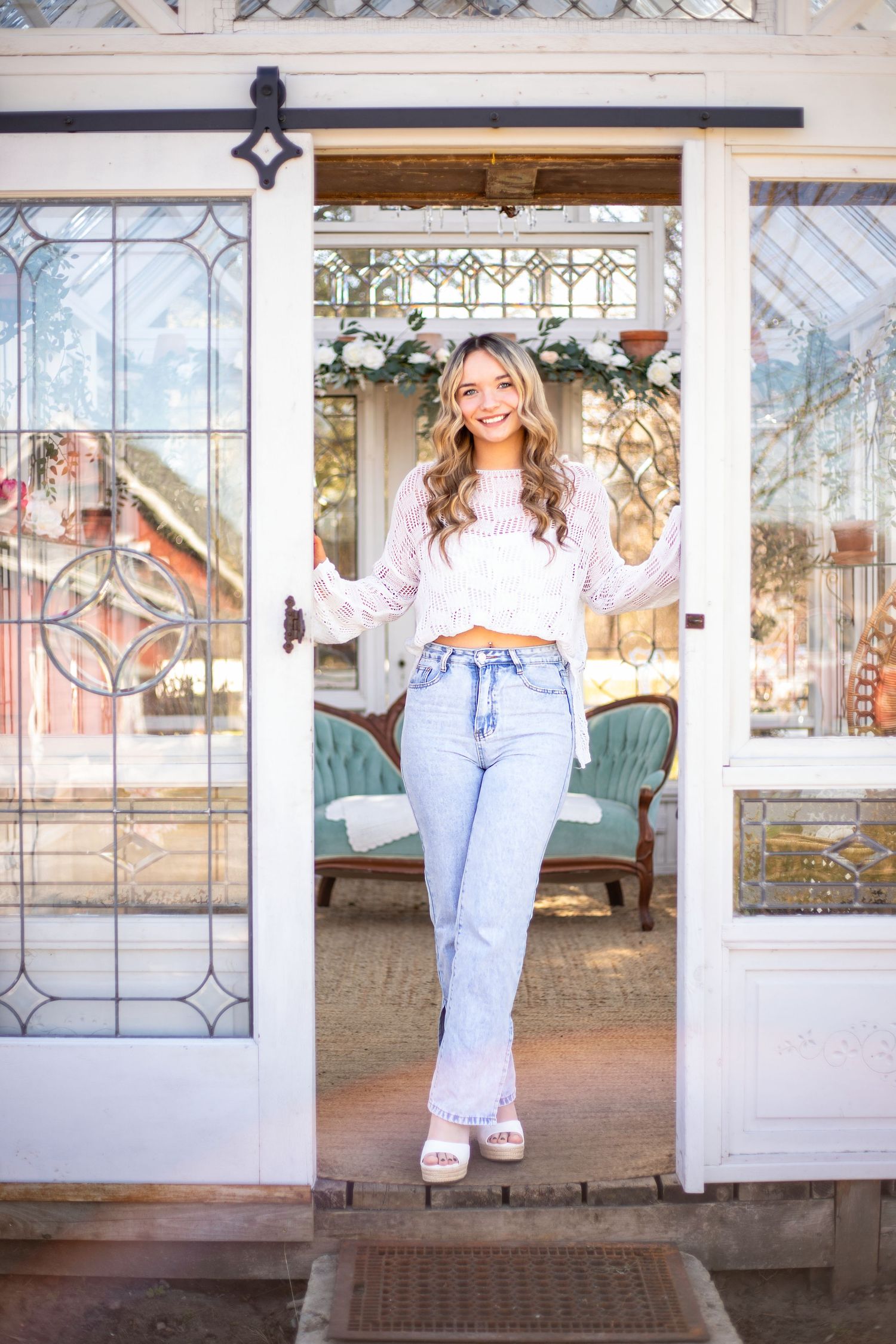 A casual photoshoot in a bright sunroom with vintage windows and a teal couch.
