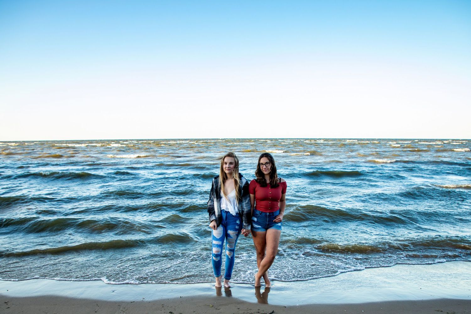 People walking along a sandy beach with waves crashing in the background.