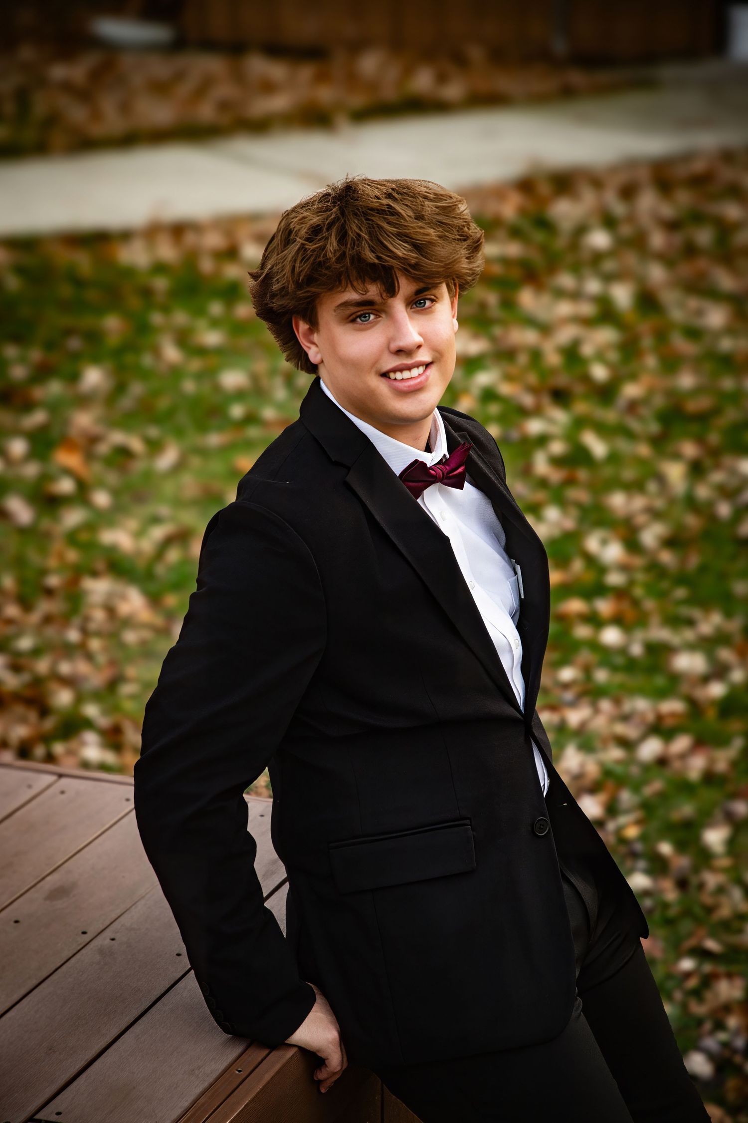 Formal portraits on a wooden deck with autumn leaves in the background.