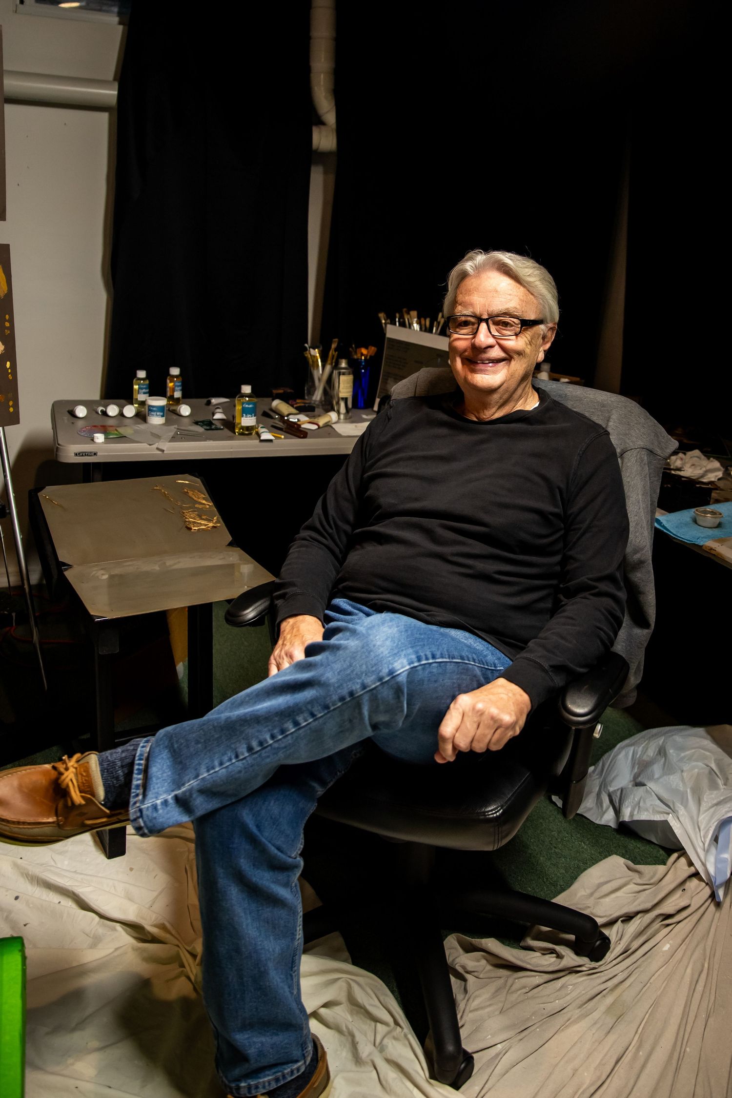 Person lounging casually on cushions in a dimly lit room.