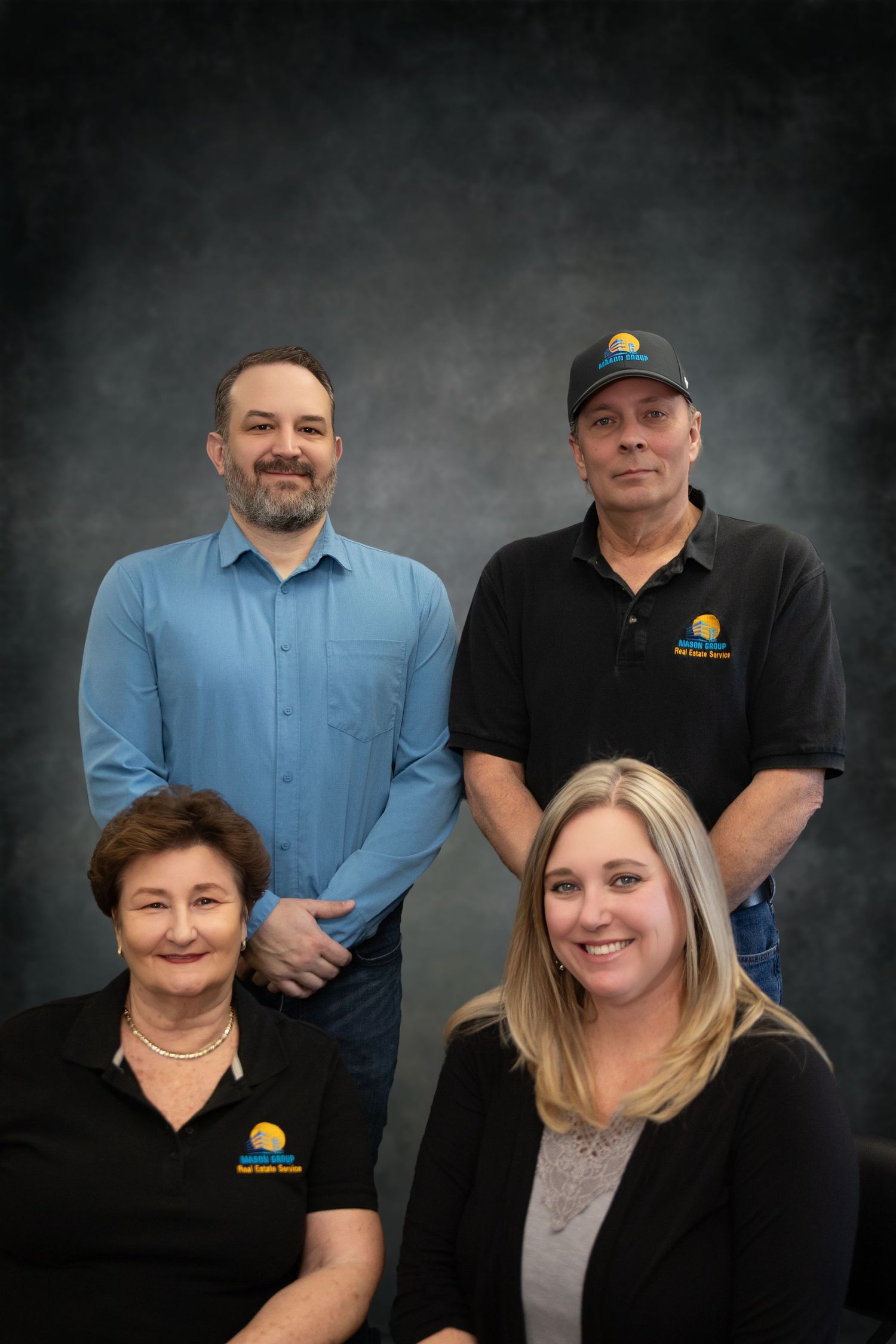 Professional corporate team photo of four people against dark background.
