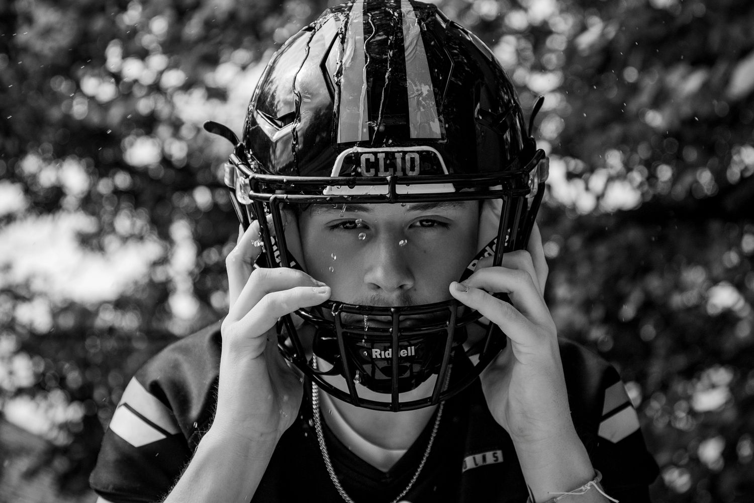 Black and white photo series of youth football players adjusting their helmets.