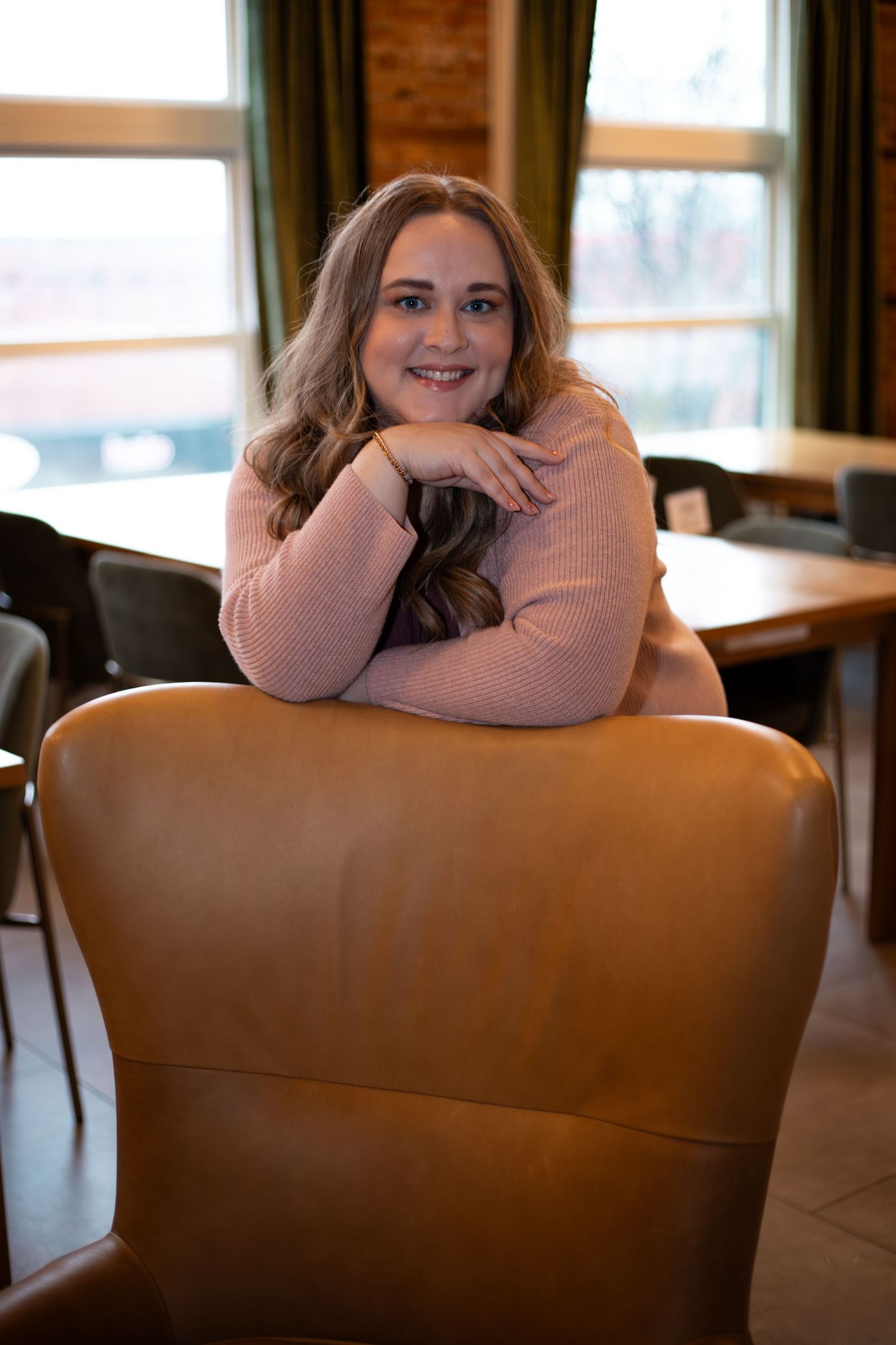 Casual portrait series on brown leather chair with soft natural window lighting.