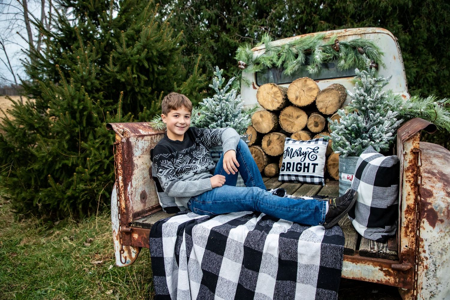 Cozy outdoor photo session with buffalo plaid blanket and rustic wood backdrop.
