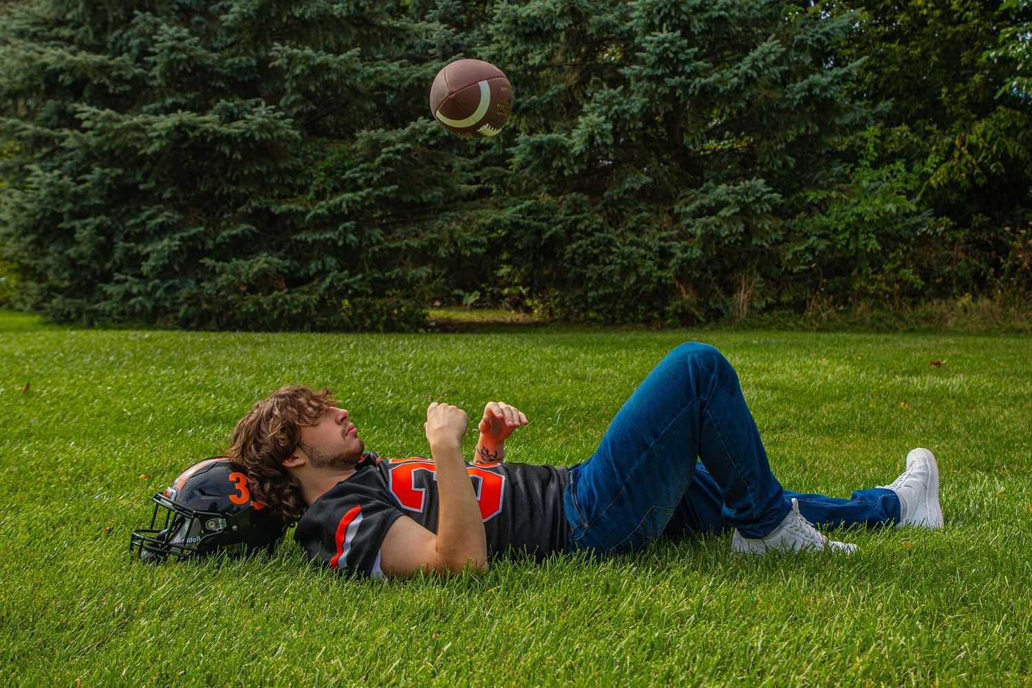 Kids laying in the grass during a sunny day at football practice.
