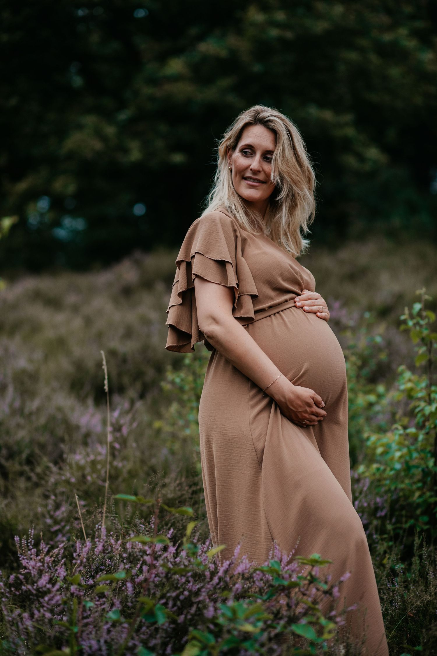Een aanstaande mama straalt tijdens een warme zwangerschapsshoot in de natuur, een bijzonder moment vol verwachting
