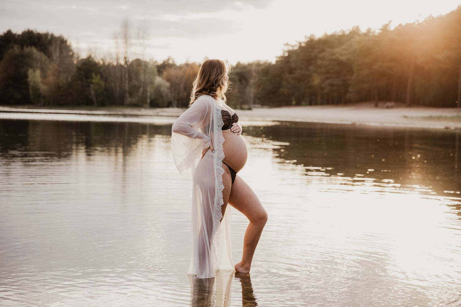 Een zwangere mama straalt tijdens een liefdevolle zwangerschapsshoot tijdens gouden uur, omringd door het warme licht.