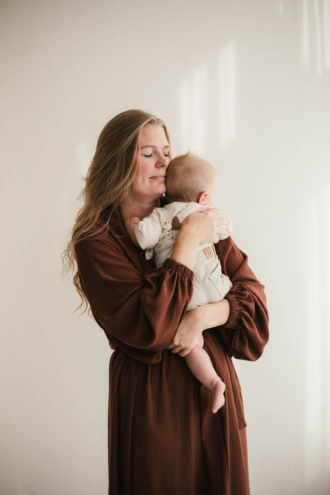Een warm en intiem moment tussen moeder en baby tijdens een ontspannen studioshoot, vol liefde en verbinding.