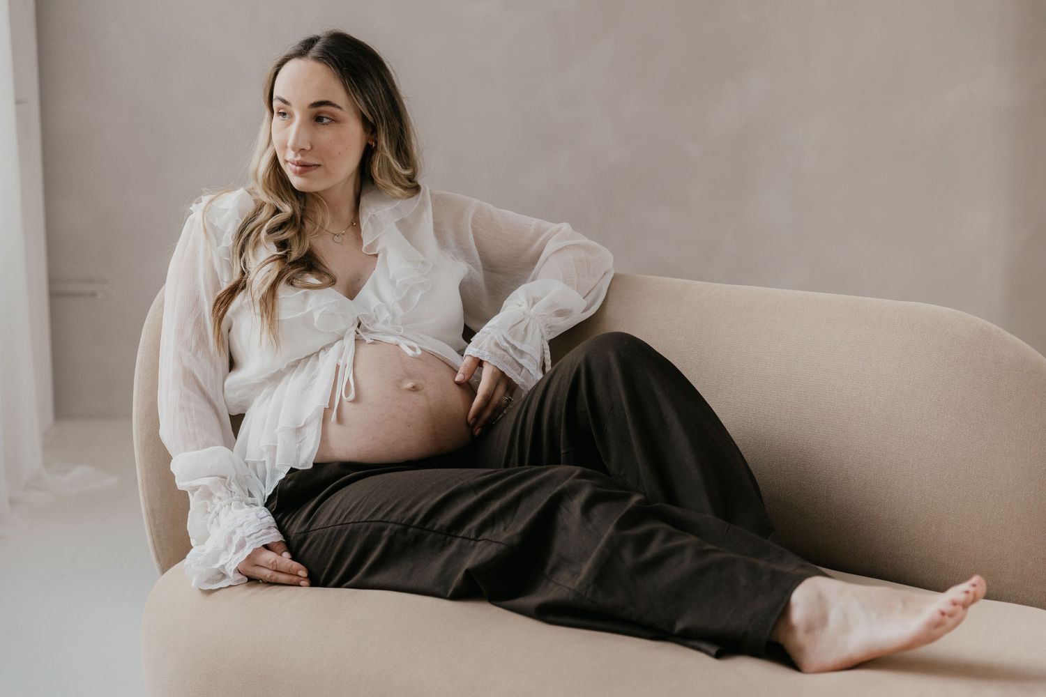 Een aanstaande mama geniet van haar zwangerschap tijdens een liefdevolle fotoshoot ineen studio, een bijzonder moment.