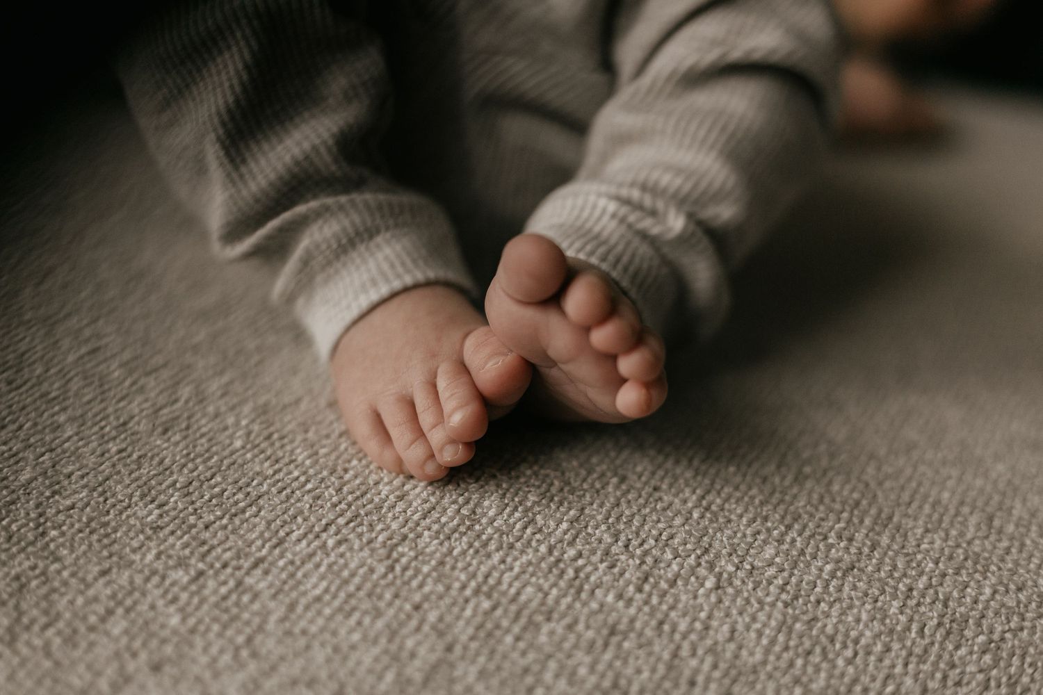 Newborn baby tijdens een ontspannen fotoshoot aan huis, waarbij de warme en vertrouwde omgeving van het gezin wordt vastgelegd.