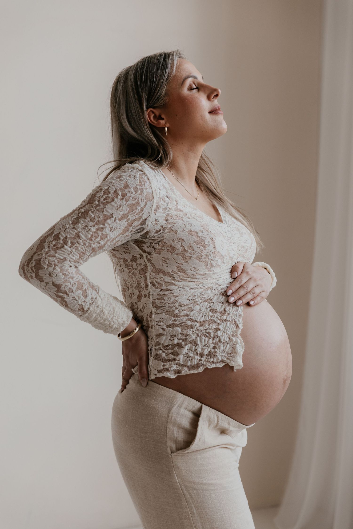 Een aanstaande mama geniet van haar zwangerschap tijdens een liefdevolle fotoshoot in een studio, een bijzonder moment.