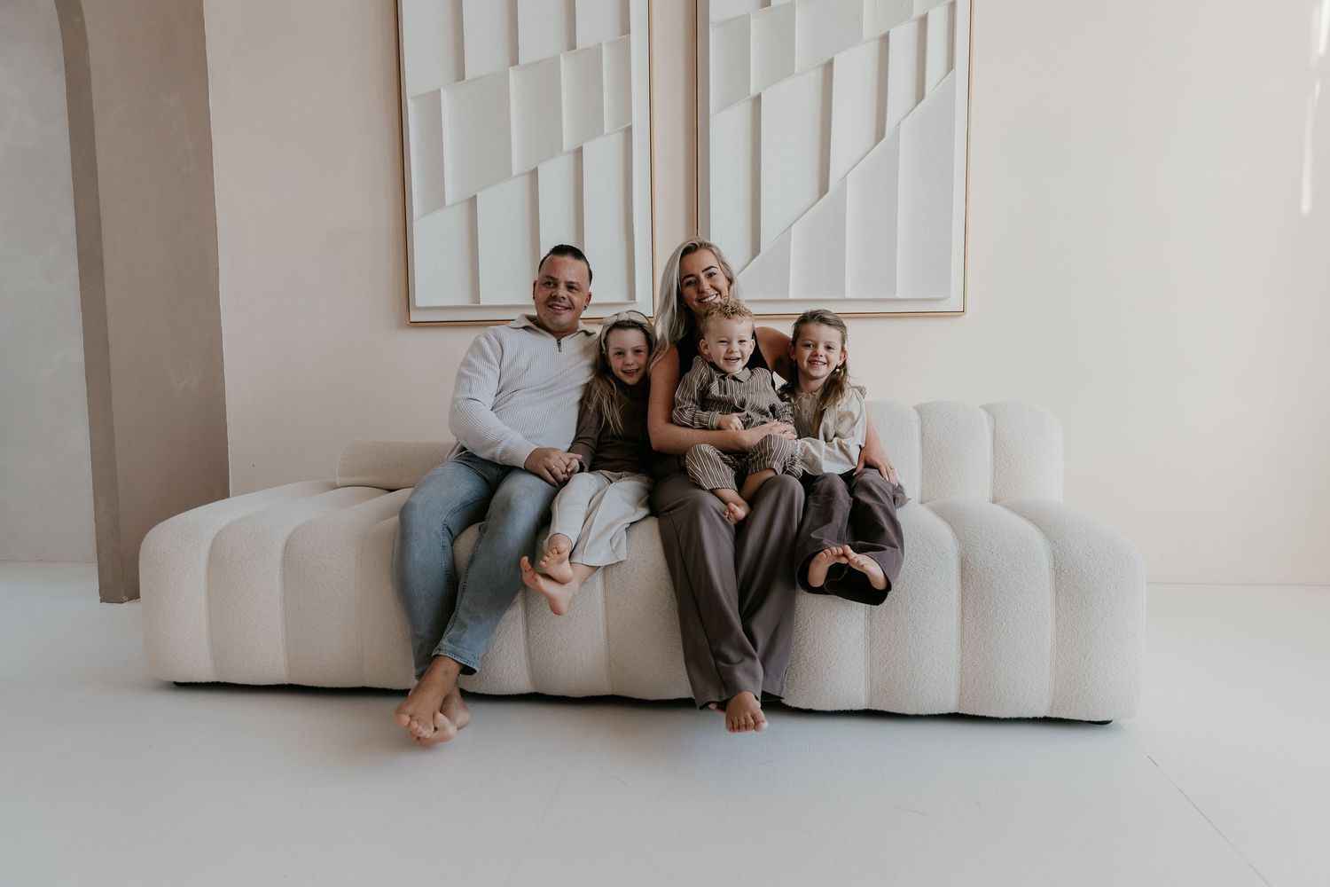 Warme familiefotografie waarbij ouders en kinderen samen genieten van een ontspannen moment in studio.