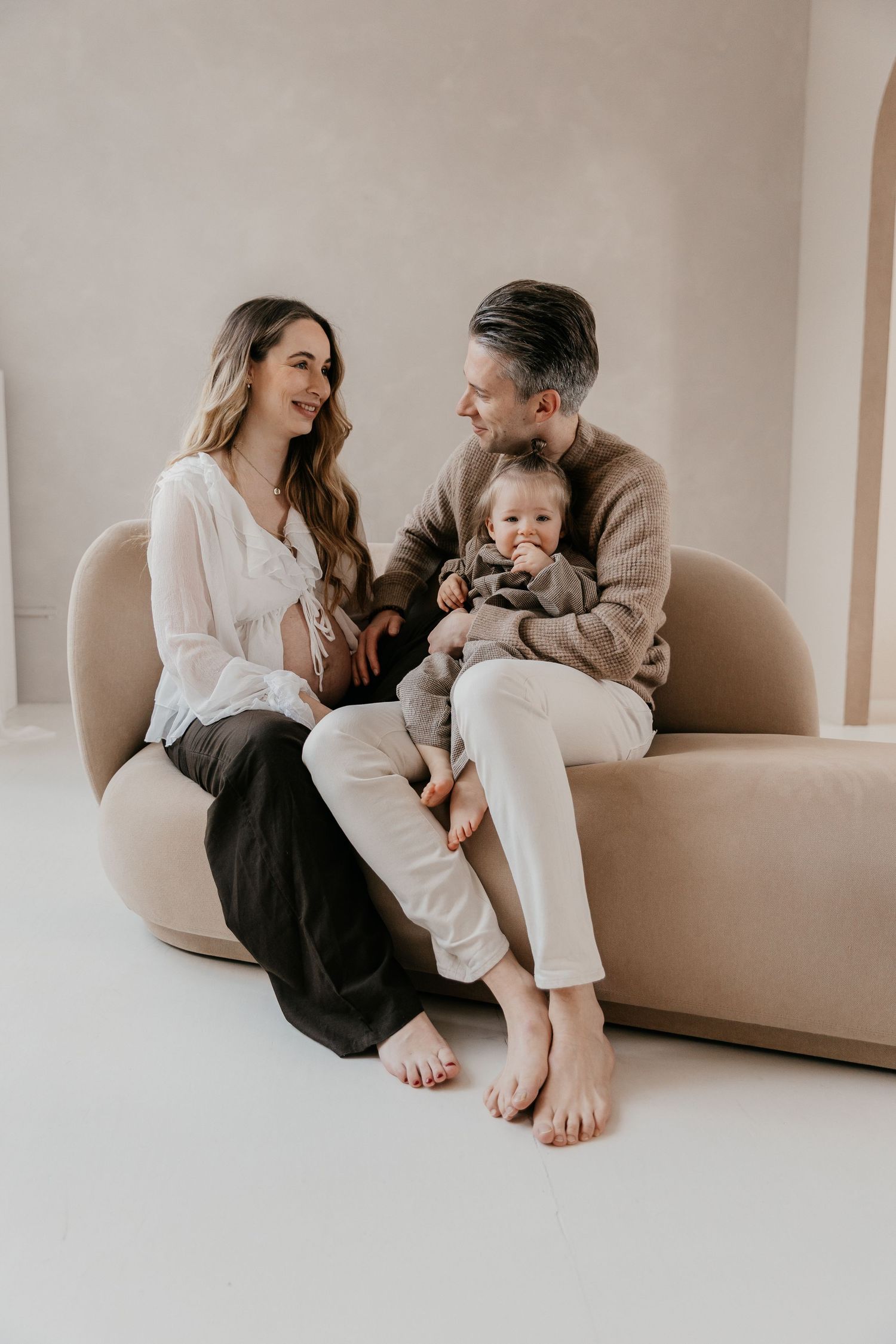 Een liefdevol gezinsmoment van aanstaande ouders en hun kleine meisje tijdens een zwangerschapsshoot in een studio.