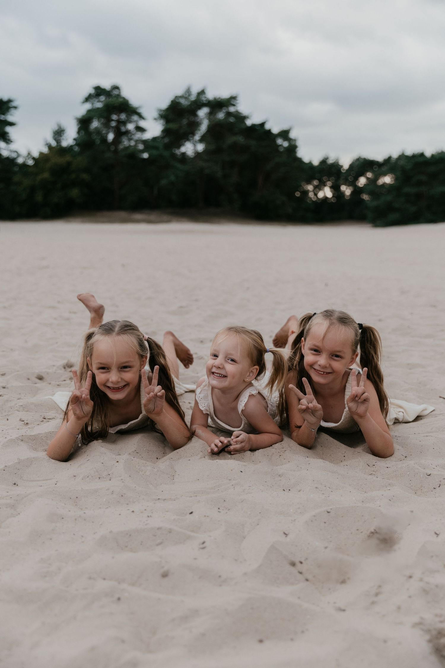 Een spontaan moment van drie zussen die samen lachen, een warme herinnering vastgelegd tijdens een familieshoot.