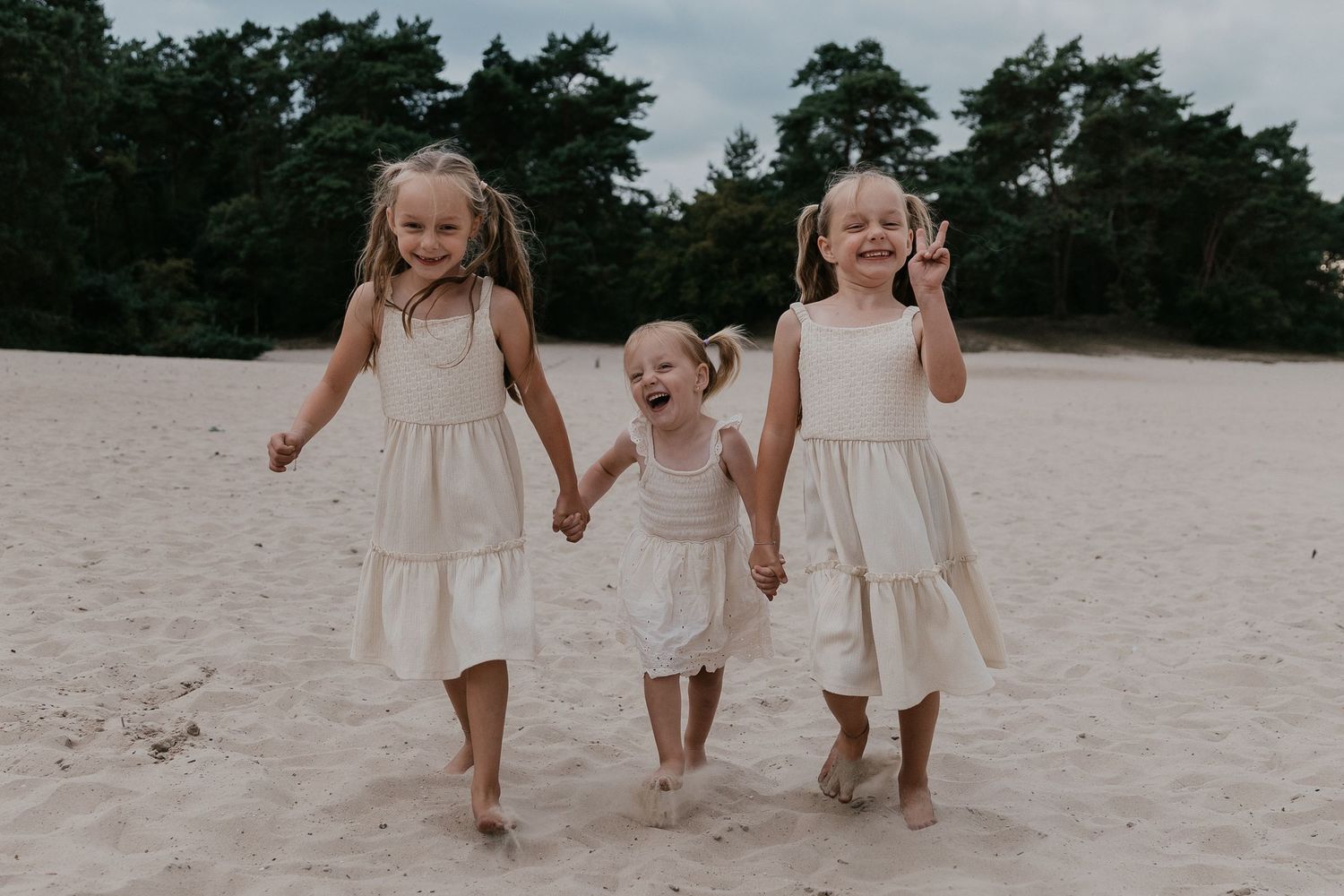 Een spontaan moment van drie zussen die samen lachen, een warme herinnering vastgelegd tijdens een familieshoot.