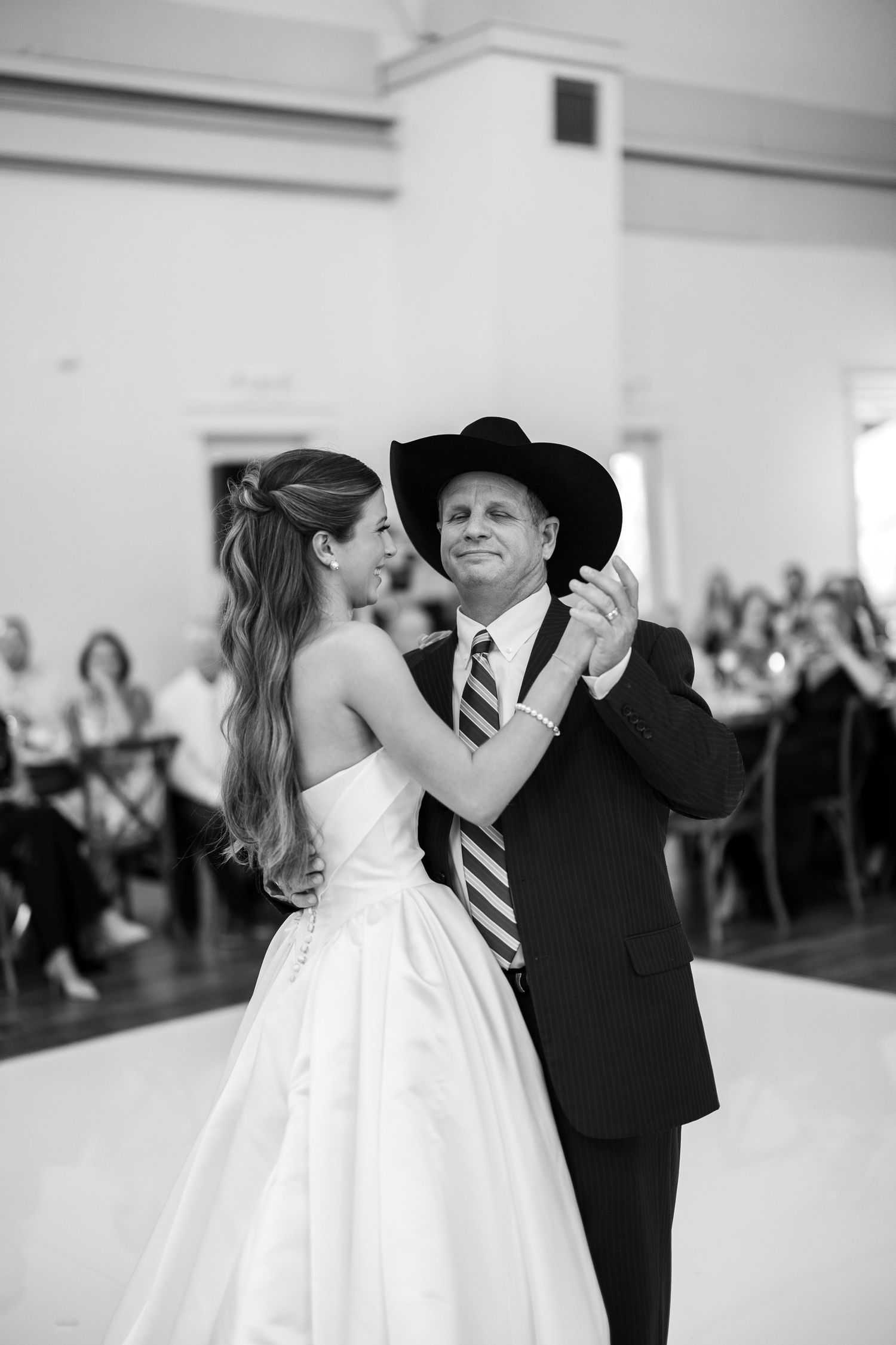 Black and white photo of a bride and her father sharing a dance at a wedding reception.