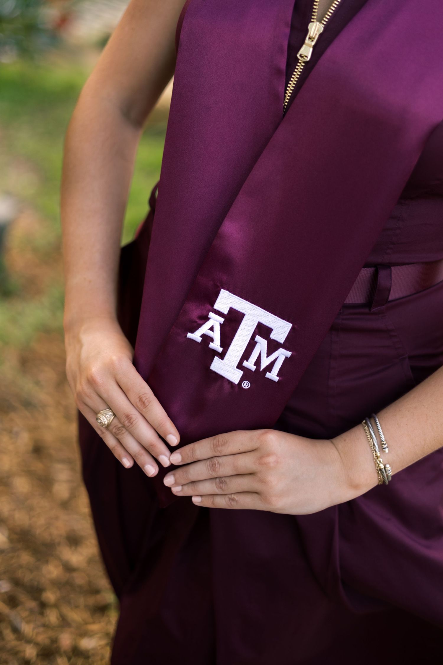 Close-up of Texas A&M graduation stole with ATM logo on maroon dress.