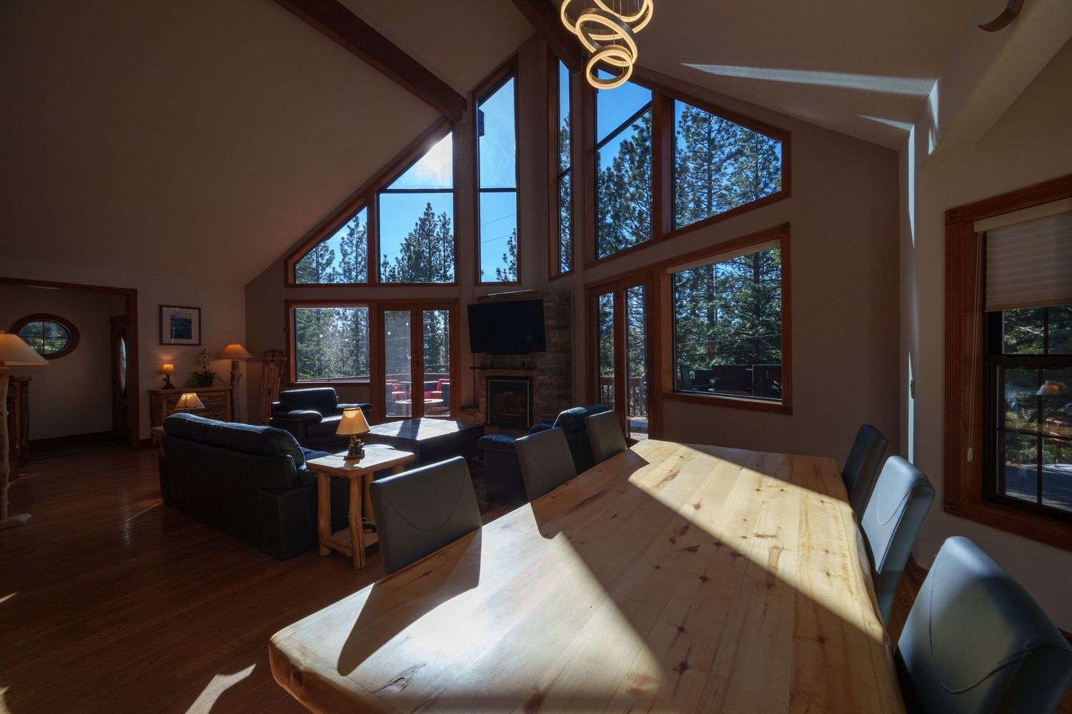 Sunlit dining area with vaulted ceiling and large windows showcasing forest views.