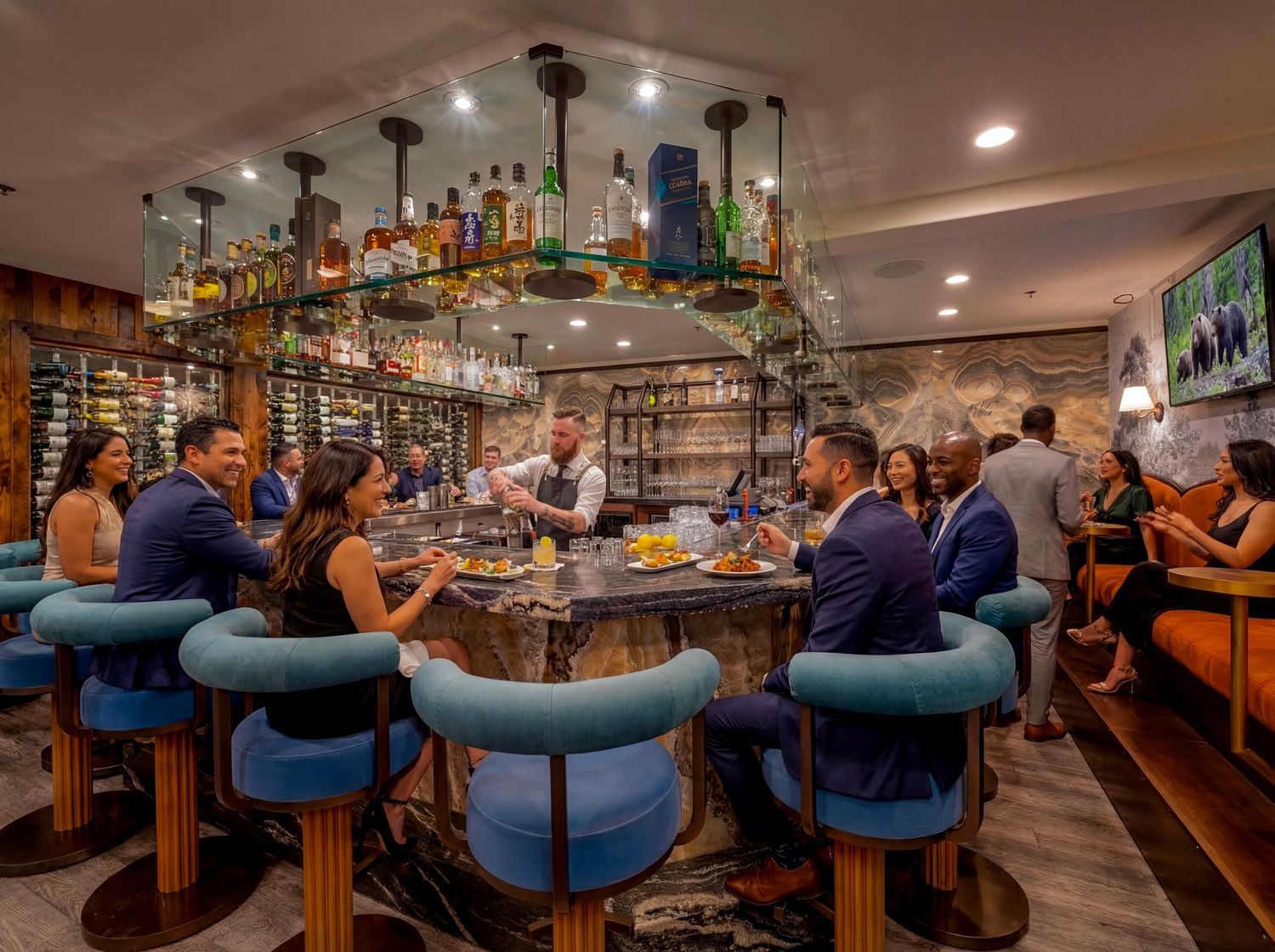 Panoramic view of a modern bar interior with blue bar stools and warm lighting showing patrons enjoying drinks.
