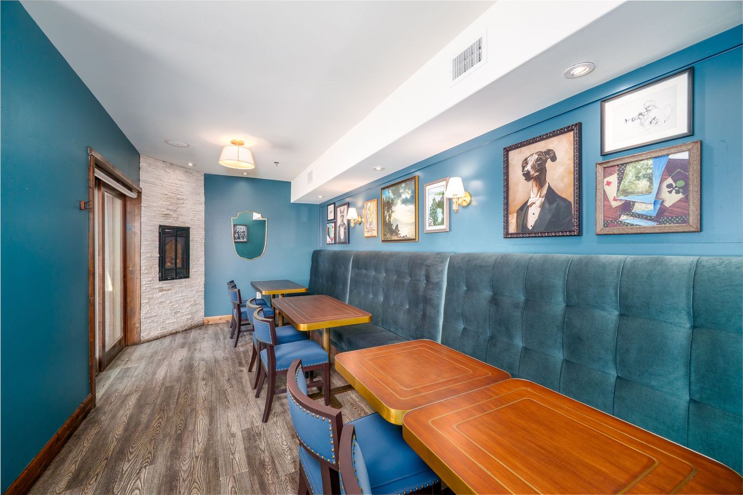 A long wooden conference table sits in a room with blue walls and framed artwork displayed.