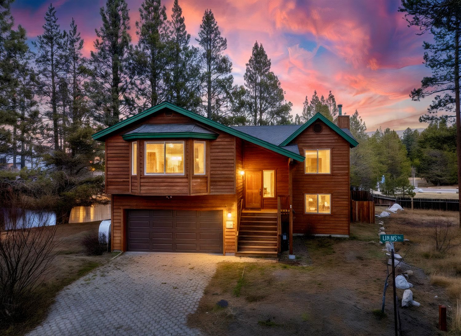 Cozy log cabins illuminated at dusk with a vibrant pink and purple sunset sky behind tall pine trees.