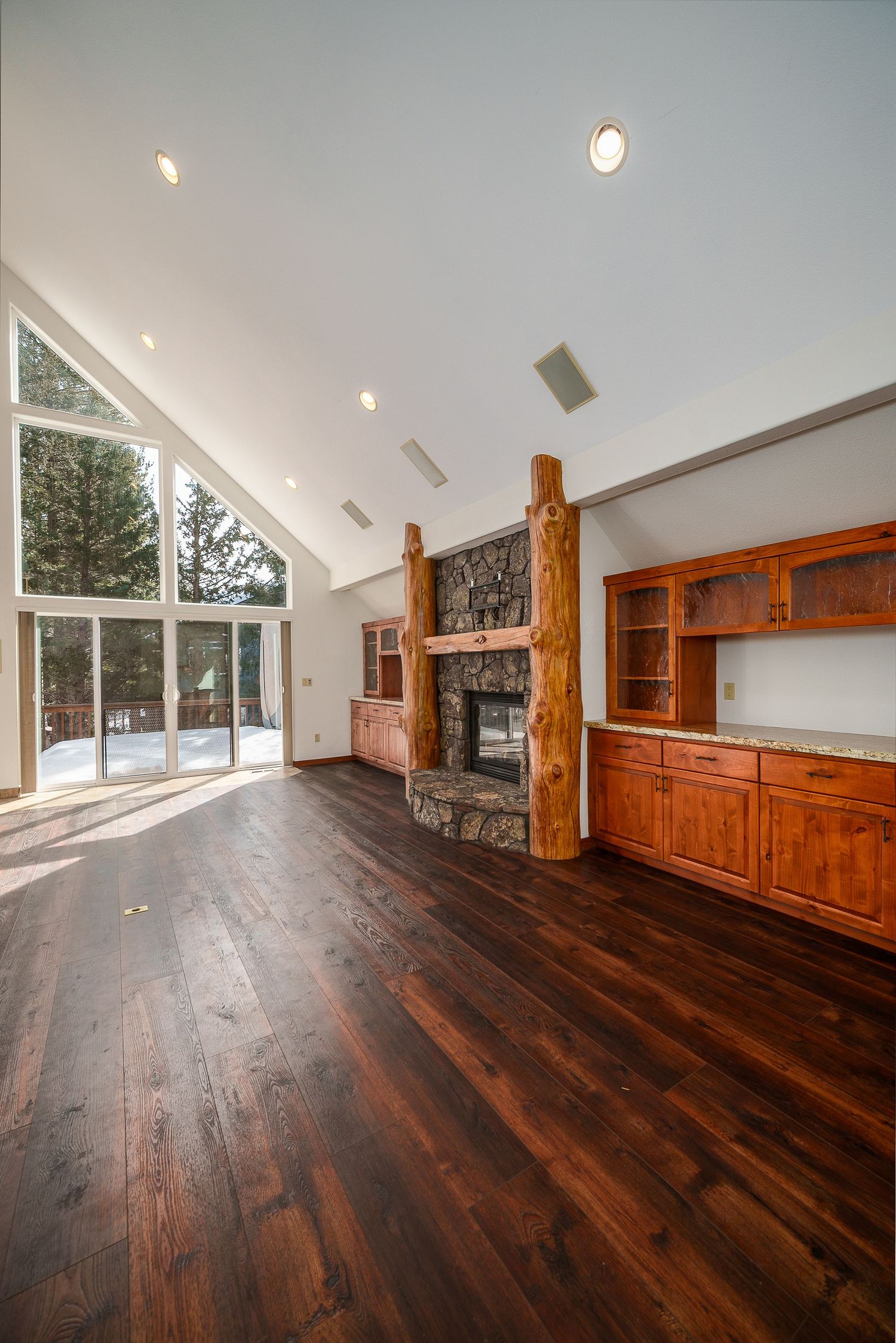 Modern living room with dark hardwood floors, white walls, and rustic wood beam accents showcases an open floor plan design.