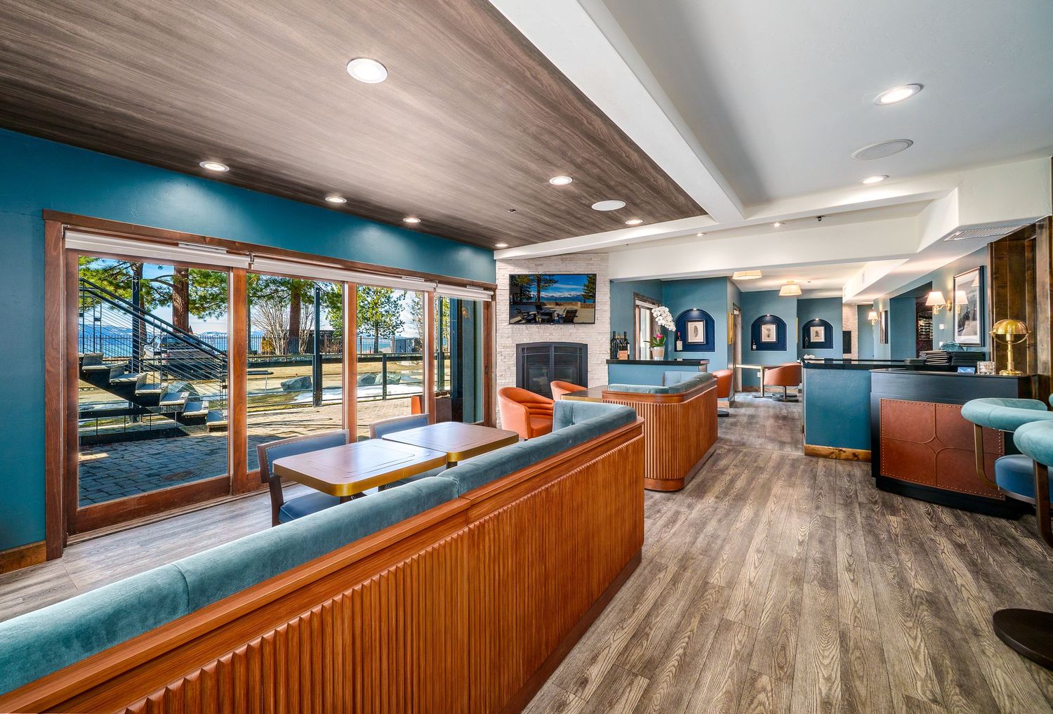 Modern restaurant interior hallway with wood paneling, blue accent walls, and recessed lighting stretches into the distance.