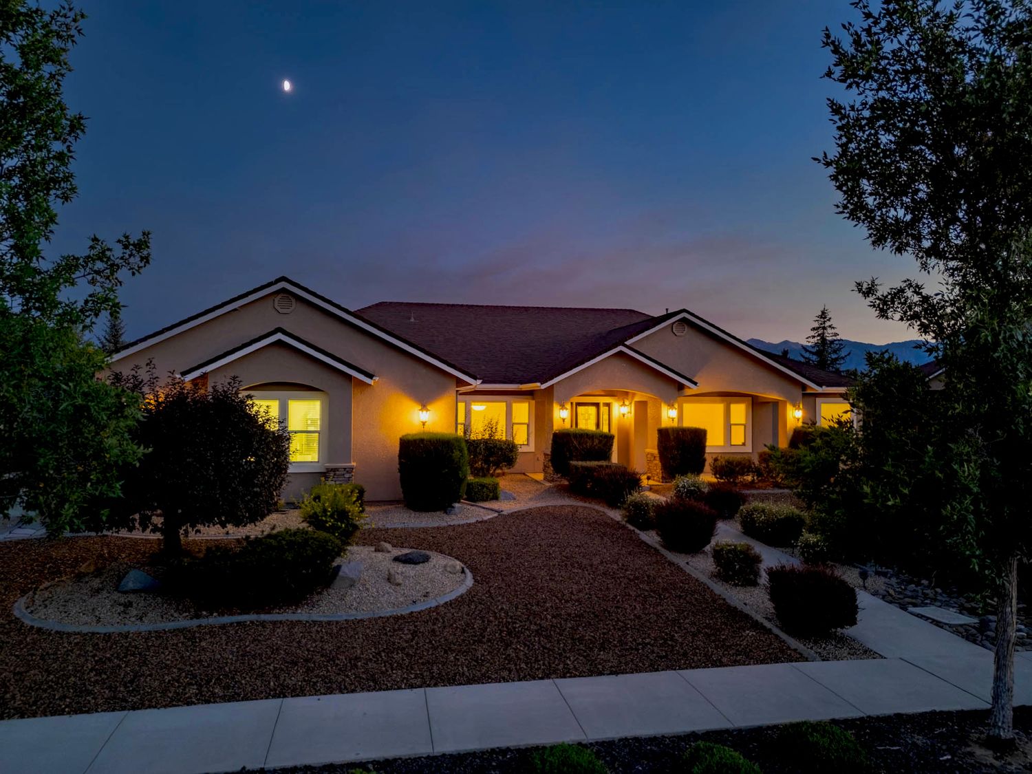 A series of twilight photos showing a modern single-story home exterior with warm glowing windows at dusk.