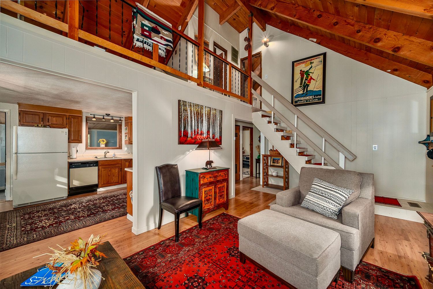 Modern cabin interior with exposed wooden beams, white walls, and a cozy living area featuring contemporary furnishings.