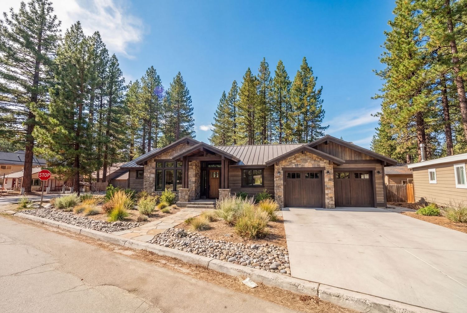 Scenic mountain property with pine trees and rustic cabins nestled along a winding road in a peaceful forest setting.