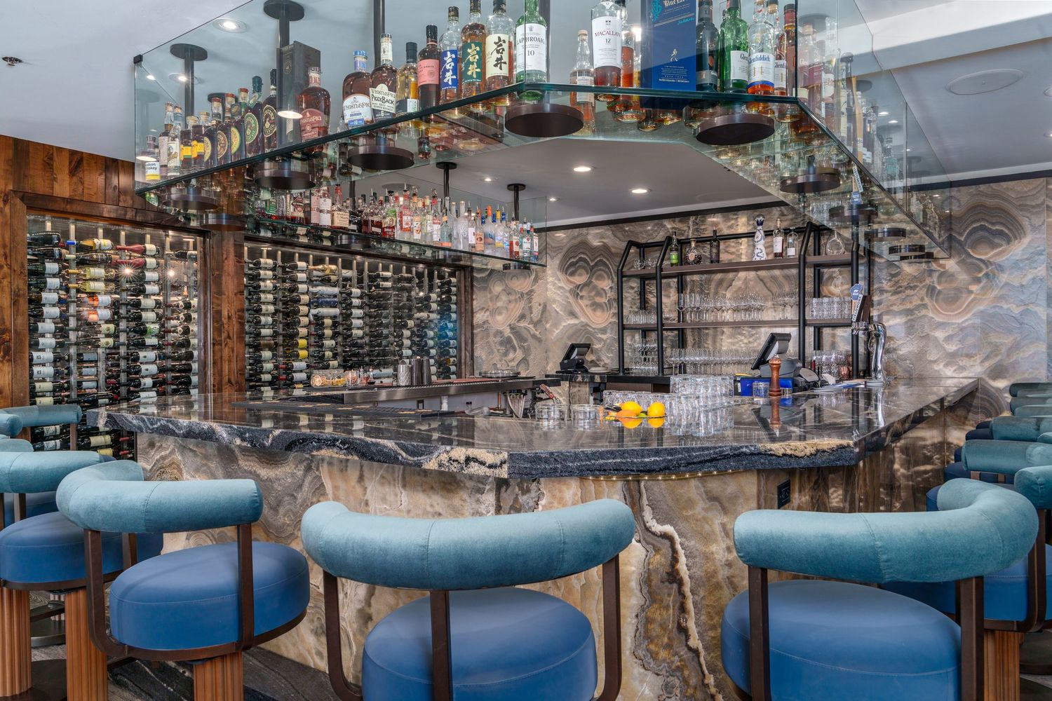 Modern restaurant interior with blue bar stools and industrial lighting fixtures hanging from exposed ceiling beams.