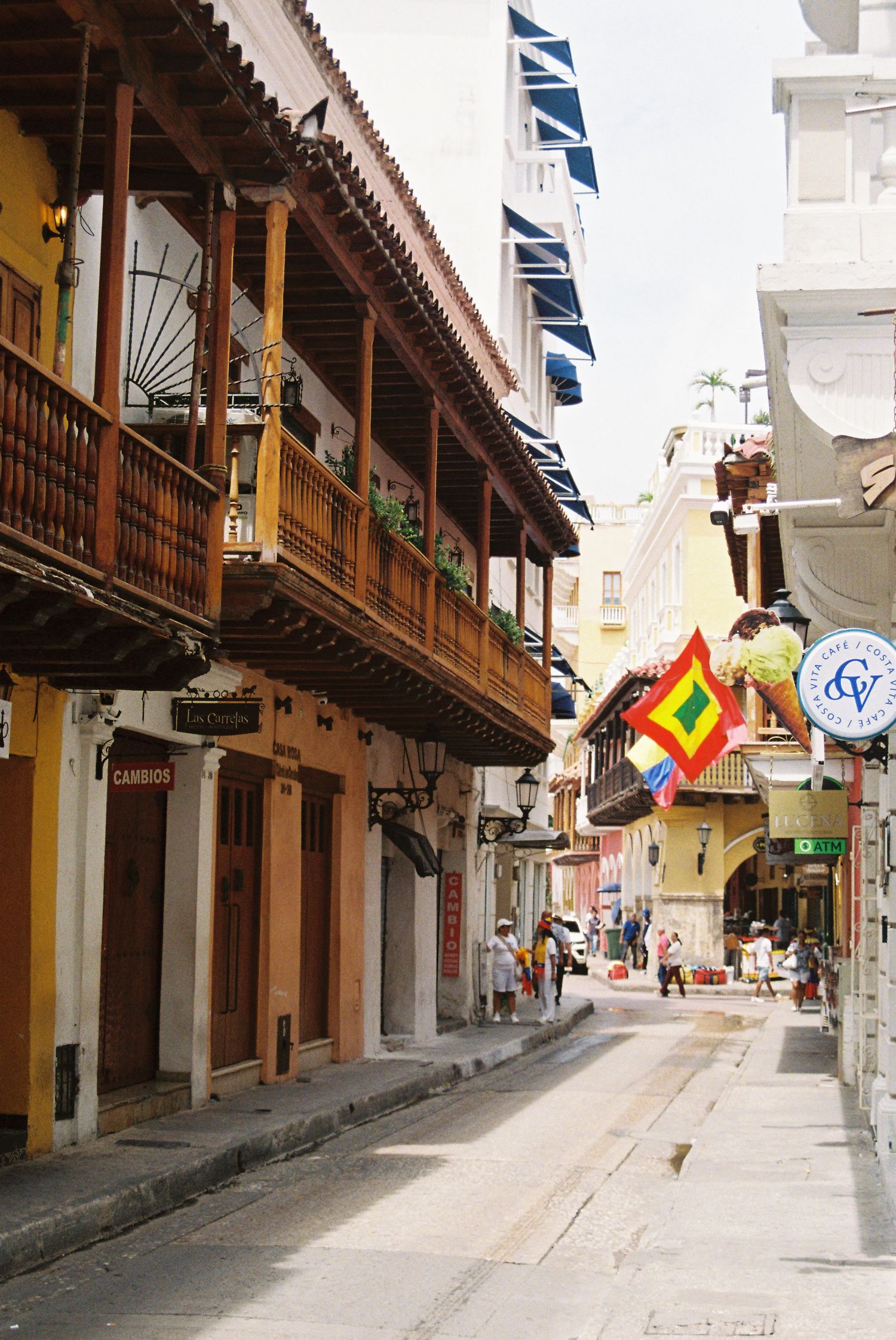 Colorful colonial street in Cartagena with wooden balconies and vibrant flag decoration.