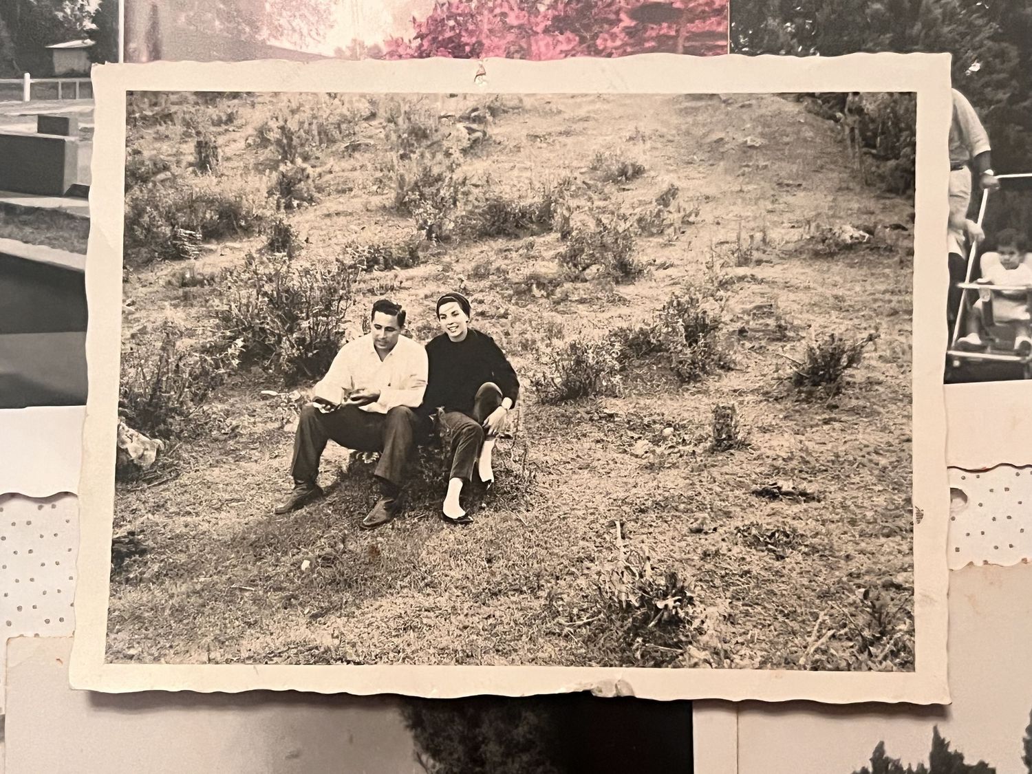 Vintage black and white photo of a couple sitting together on a grassy hillside outdoors.