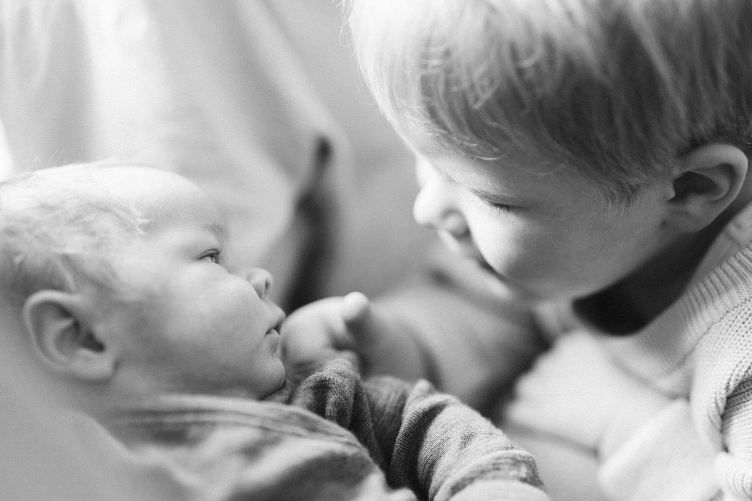 Geschwisterkind schaut das Baby an, Schwarzweiß