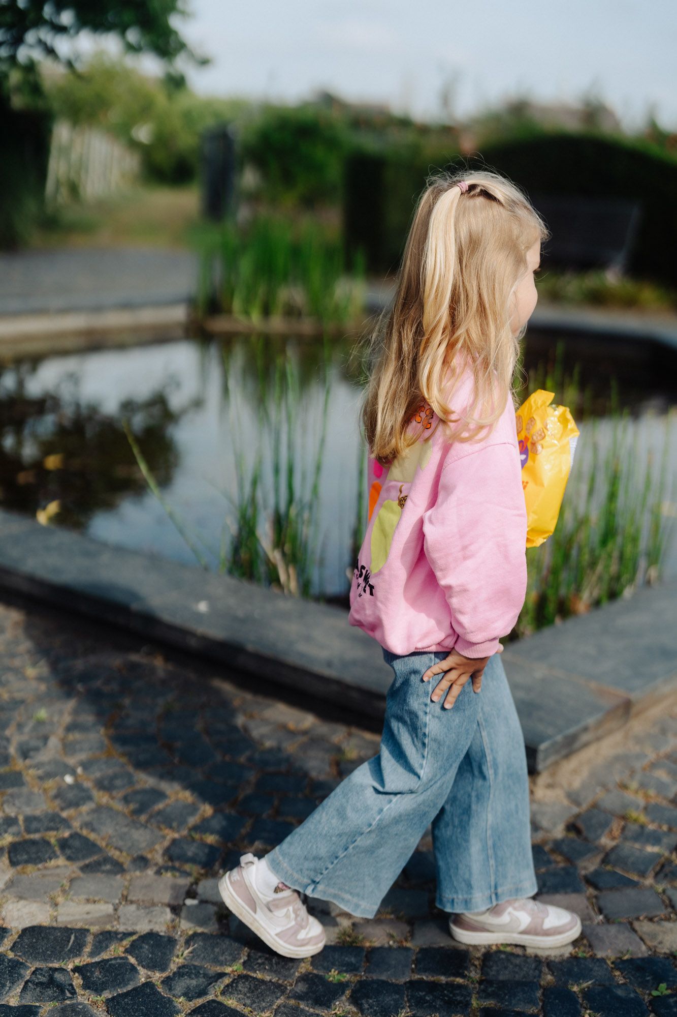 Mädchen in rosa Jacke am Teichufer