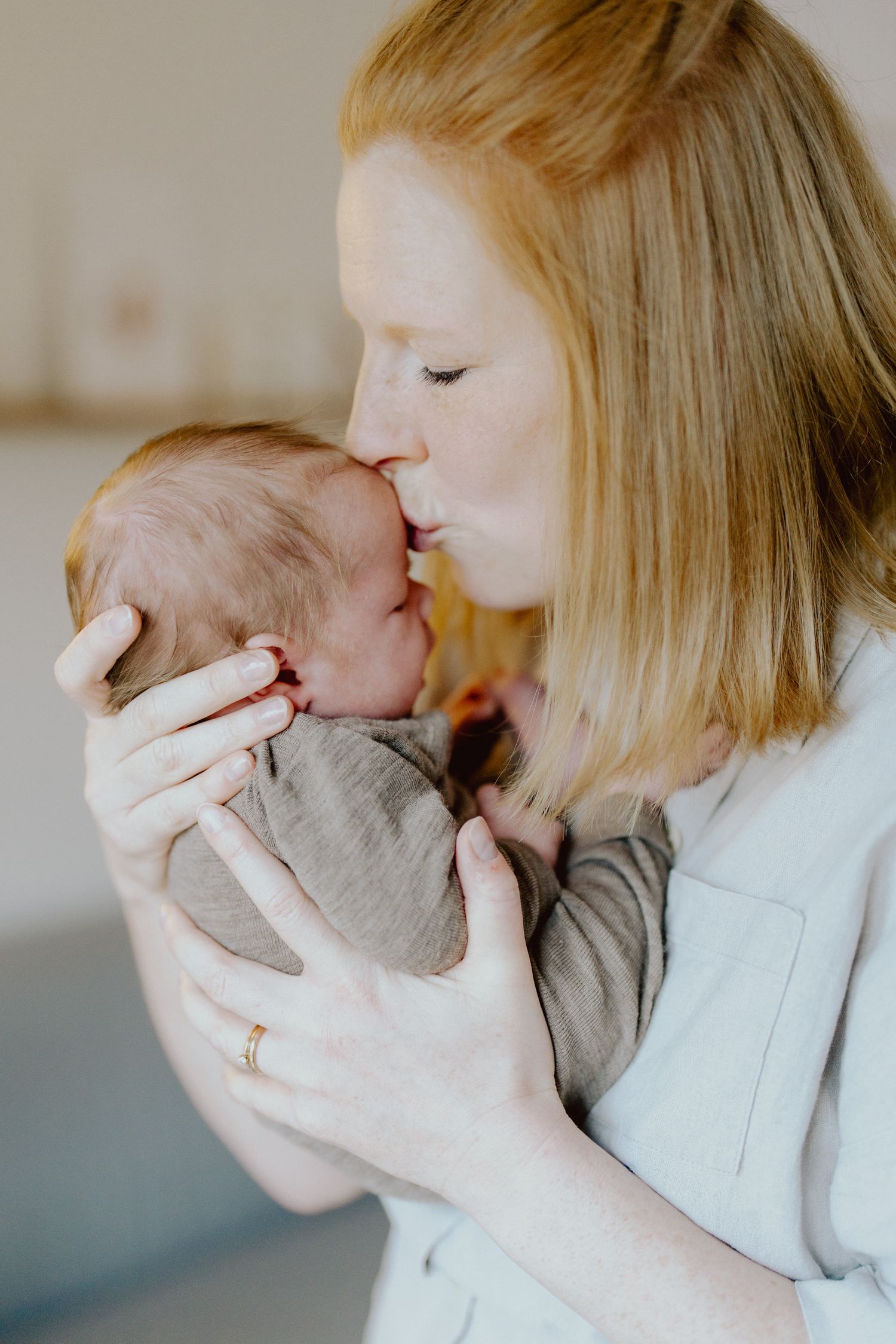 Mutter küsst ihr Neugeborenes, Newborn-Shooting zuhause