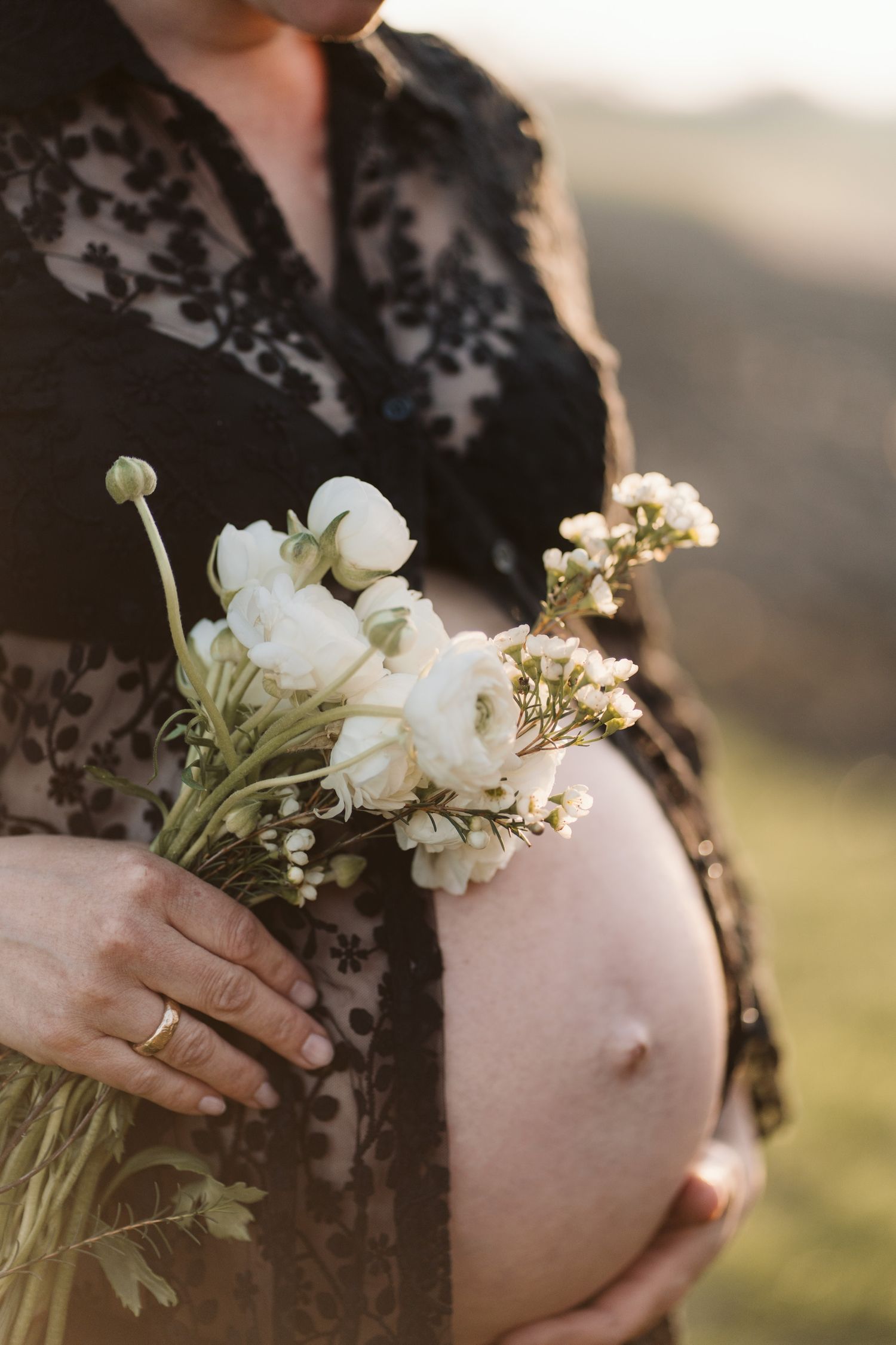 Babybauch mit Blumenstrauß, Detailaufnahme