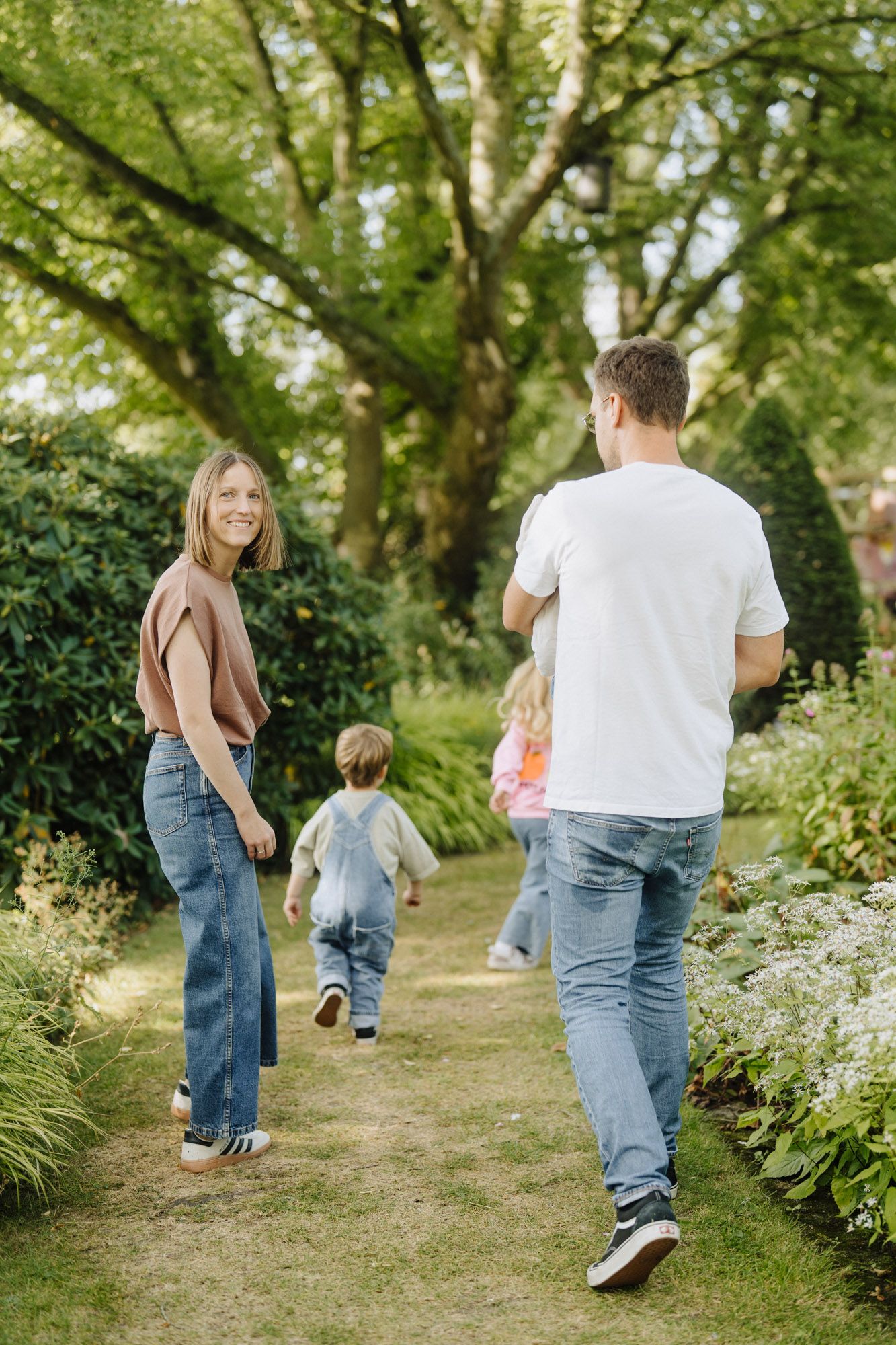 Eltern spazieren mit ihren Kindern durch einen Garten