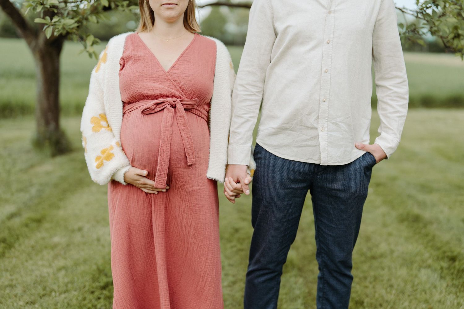 Schwangere und Partner unter Obstbäumen, Babybauch-Shooting