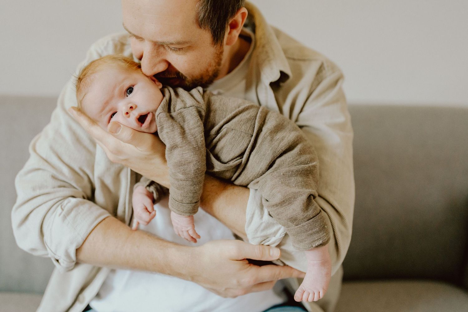 Vater hält sein Baby im Arm, Newborn-Shooting zuhause