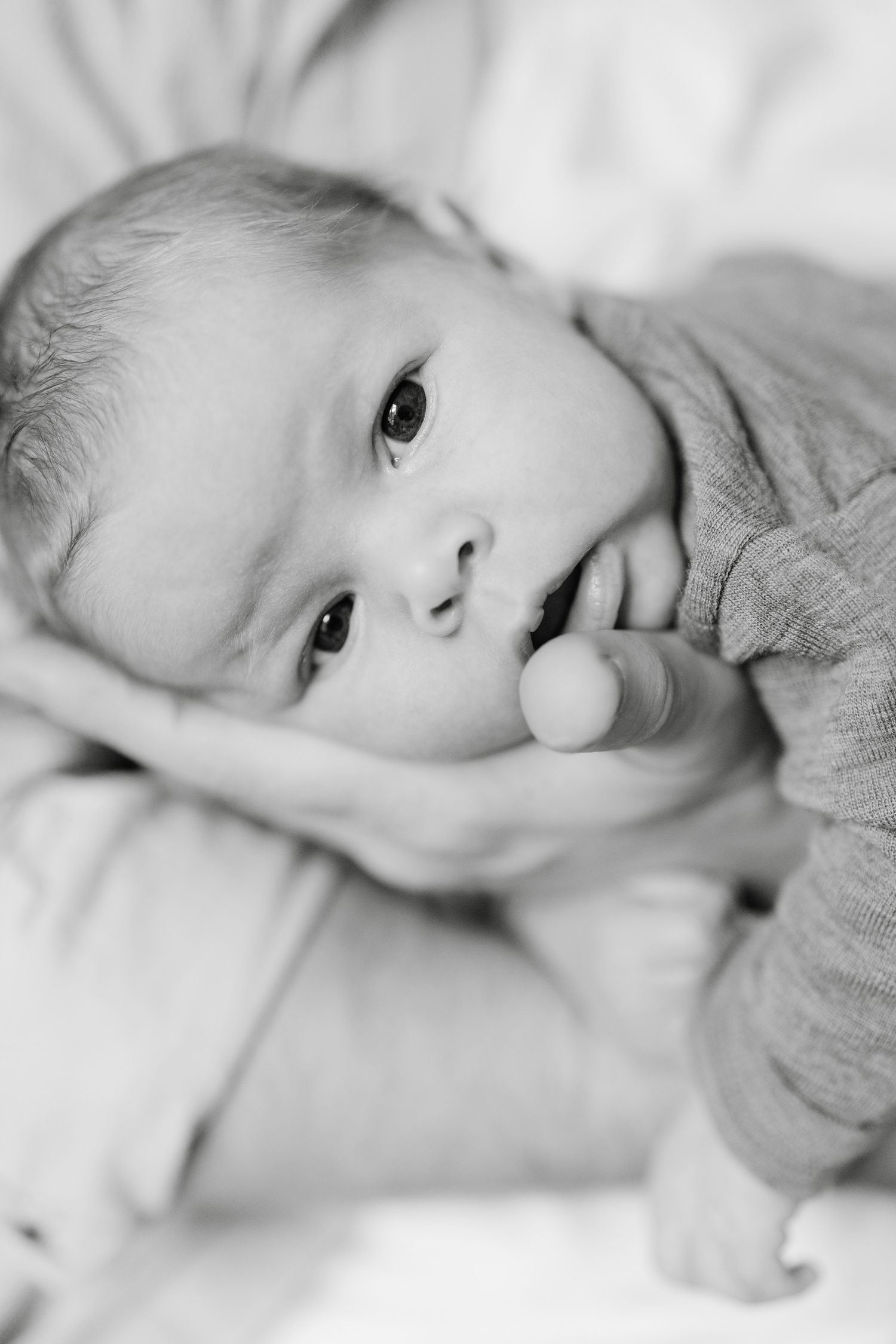 Baby in Bauchlage schaut in die Kamera, Schwarzweiß